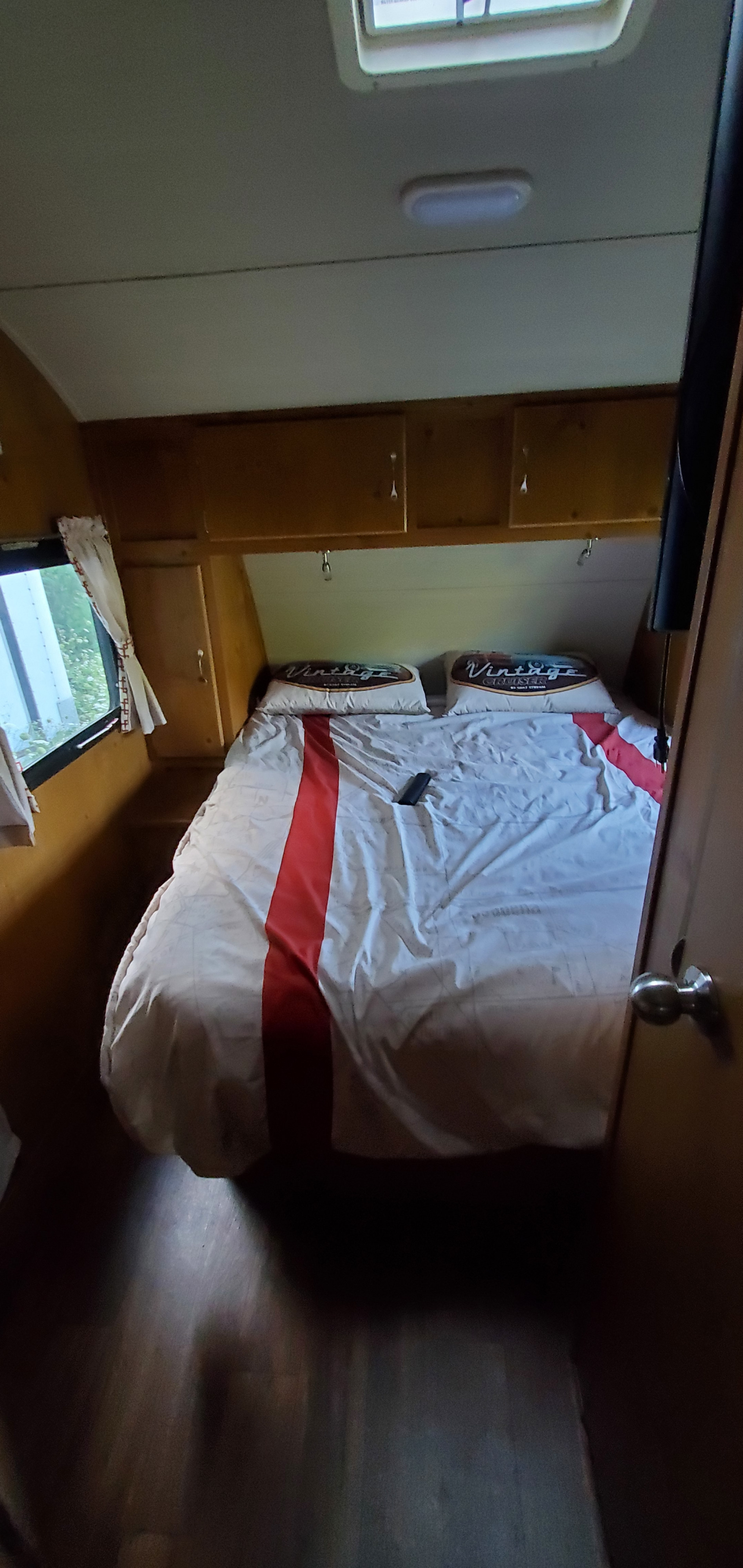 RV rental bedroom: a cozy space with a bed, Vintage Cruiser pillows, wood cabinets, and TV.. Gulf Stream Vintage Friendship 2019