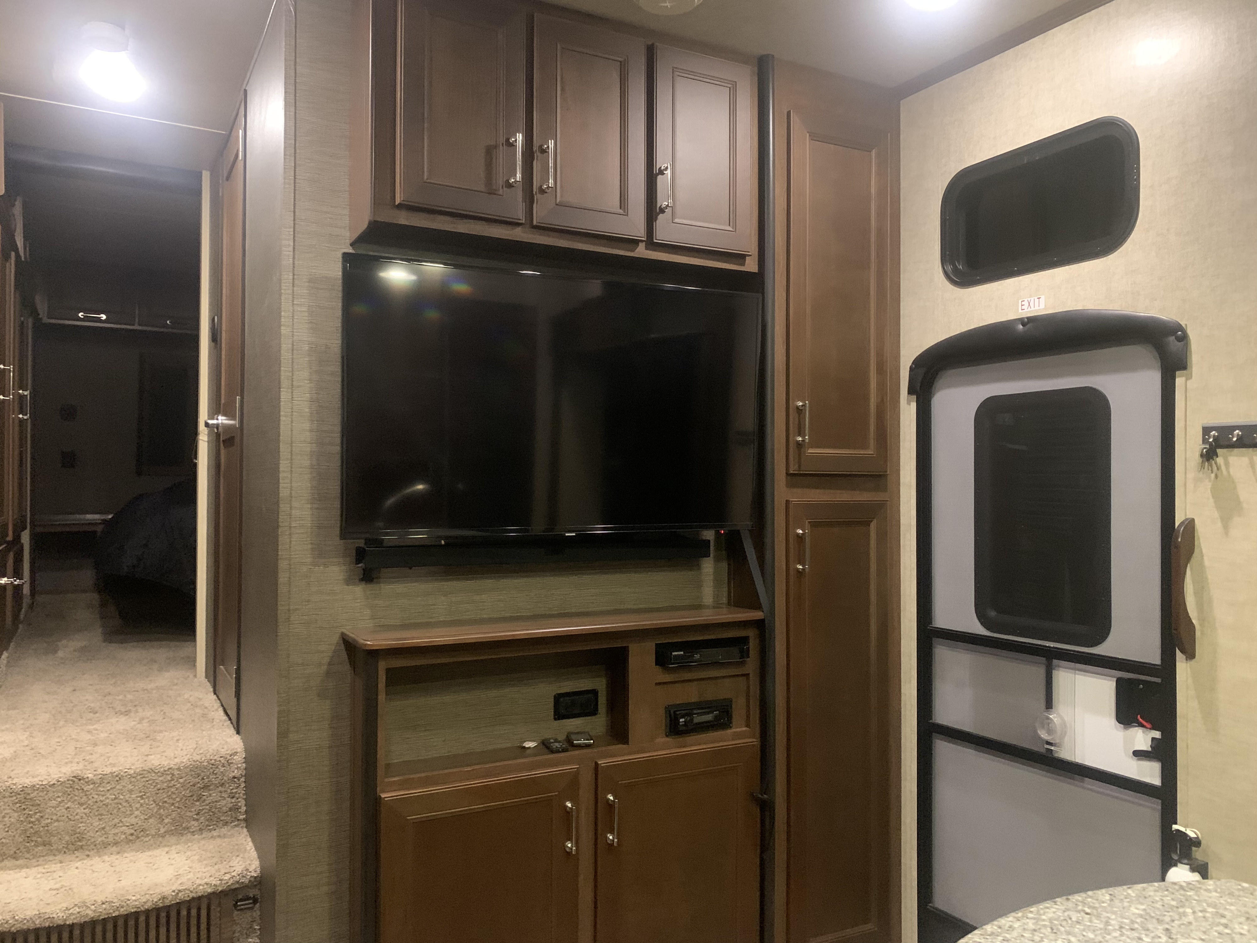 Explore this RV rental's cozy interior: entertainment center, storage, carpeted steps to bedroom, and exit.. Keystone Fuzion 2015