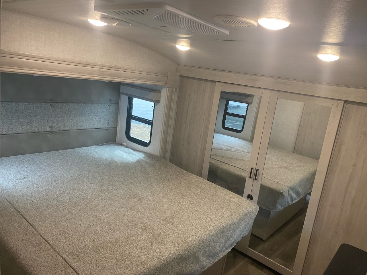 Bright RV rental bedroom interior featuring a large bed, window, and mirrored closet for ample storage.. EAST TO WEST TANDARA 320RL 2022