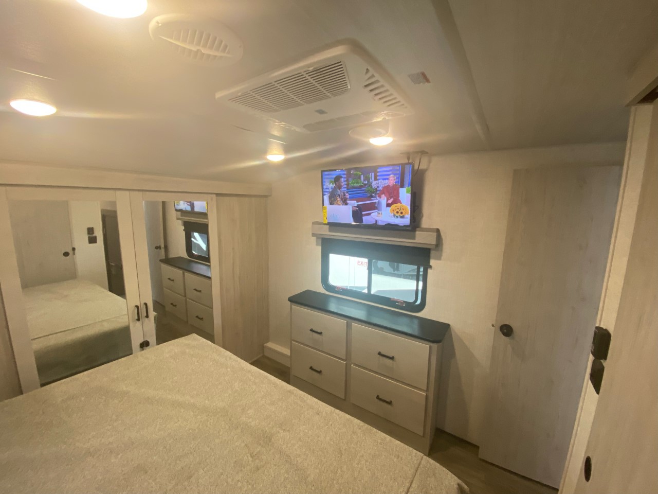 Bright RV rental bedroom with comfy bed, TV above dresser, mirrored closet, window, and ceiling AC. A cozy travel space.. EAST TO WEST TANDARA 320RL 2022