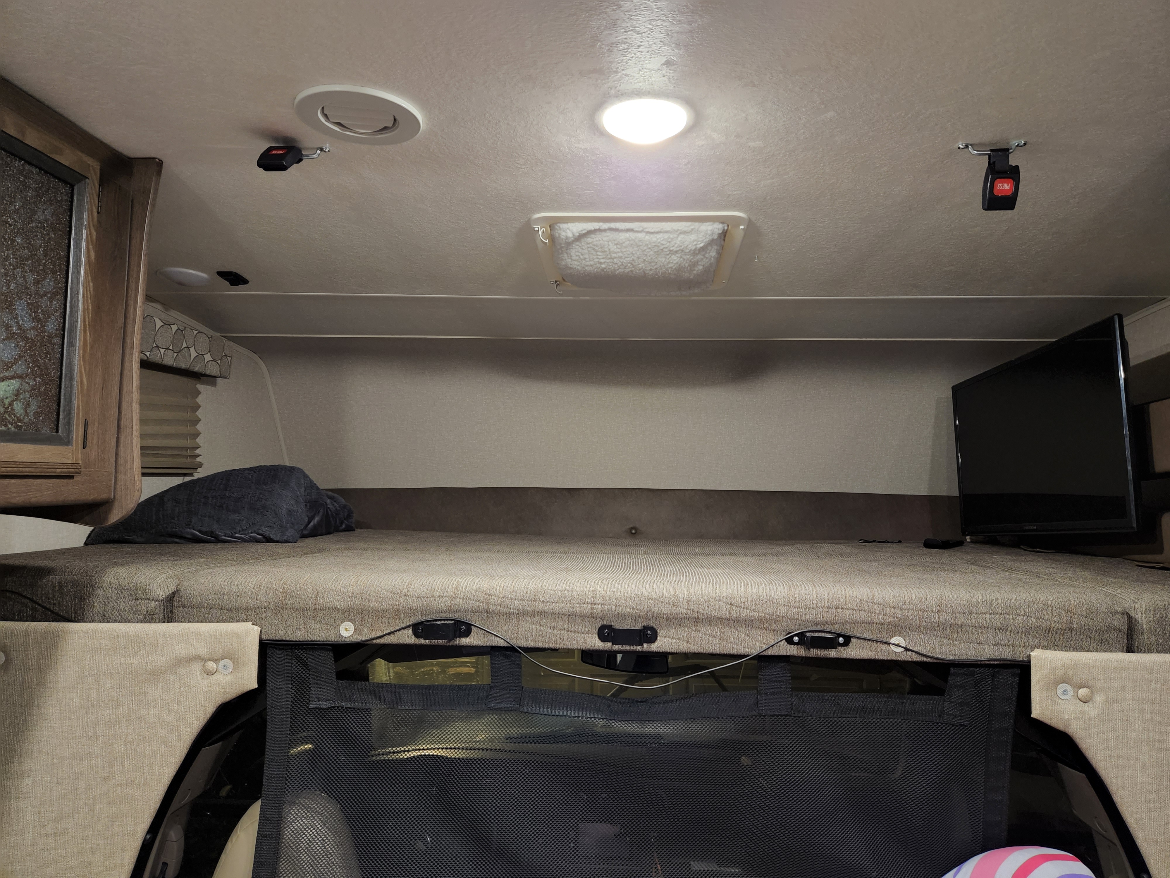 This RV rental's cab-over bunk offers a cozy sleeping area with TV, overhead light, and safety net.. Forest River Coachmen Freelander 2019