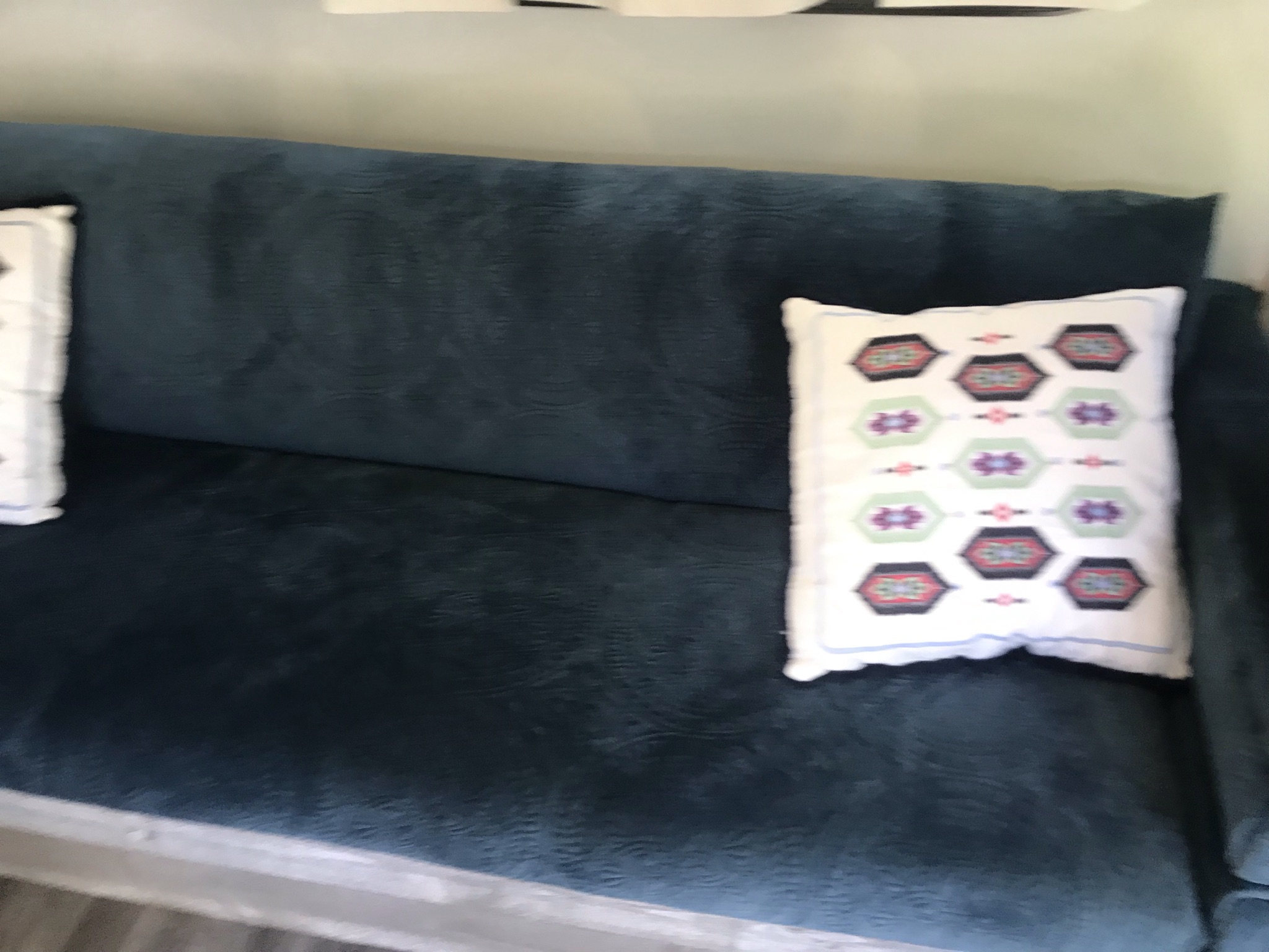 Comfortable teal sofa and patterned pillow inside an RV rental.. Thor Vegas 2016