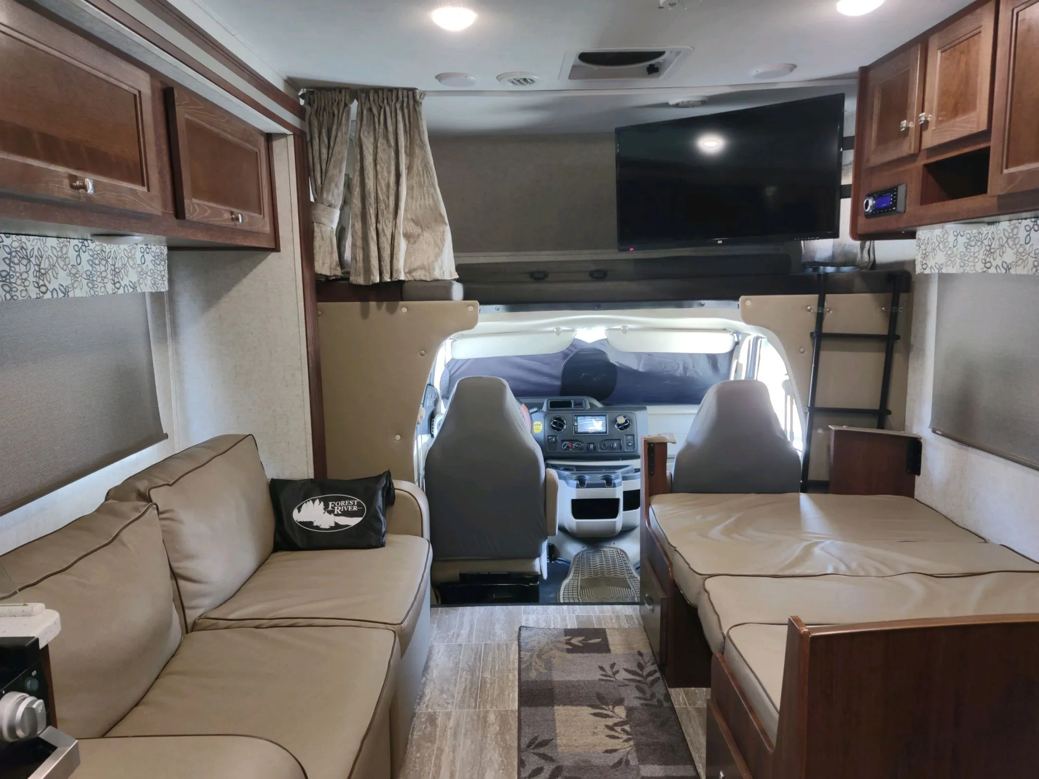 Spacious RV rental interior featuring a comfortable sofa, bed, and forward cockpit view. Ready for your next adventure.. Forester LE 2020