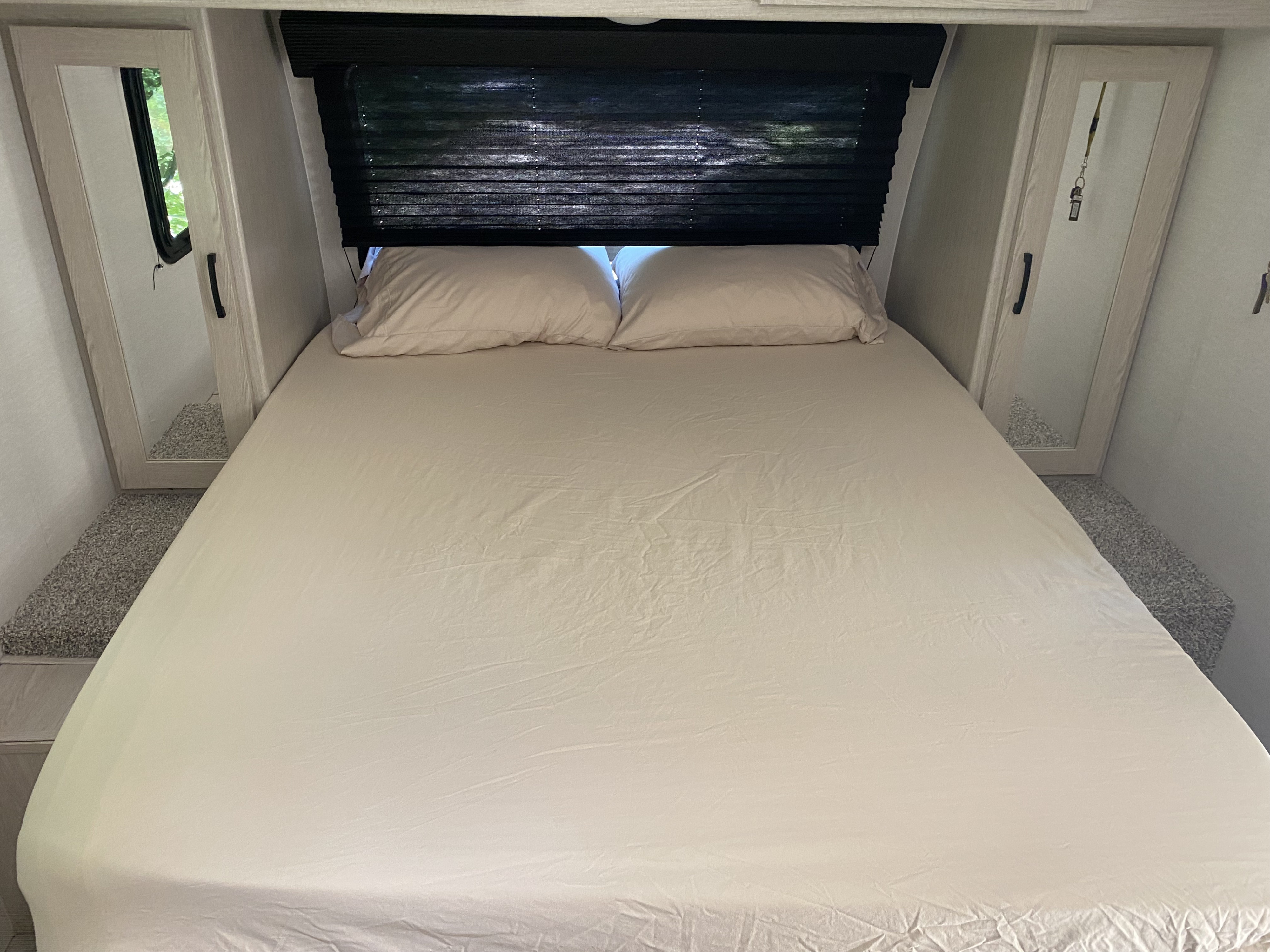 Comfortable RV rental bedroom featuring a clean bed, overhead blind, and mirrored closets.. Coachmen Apex 2021