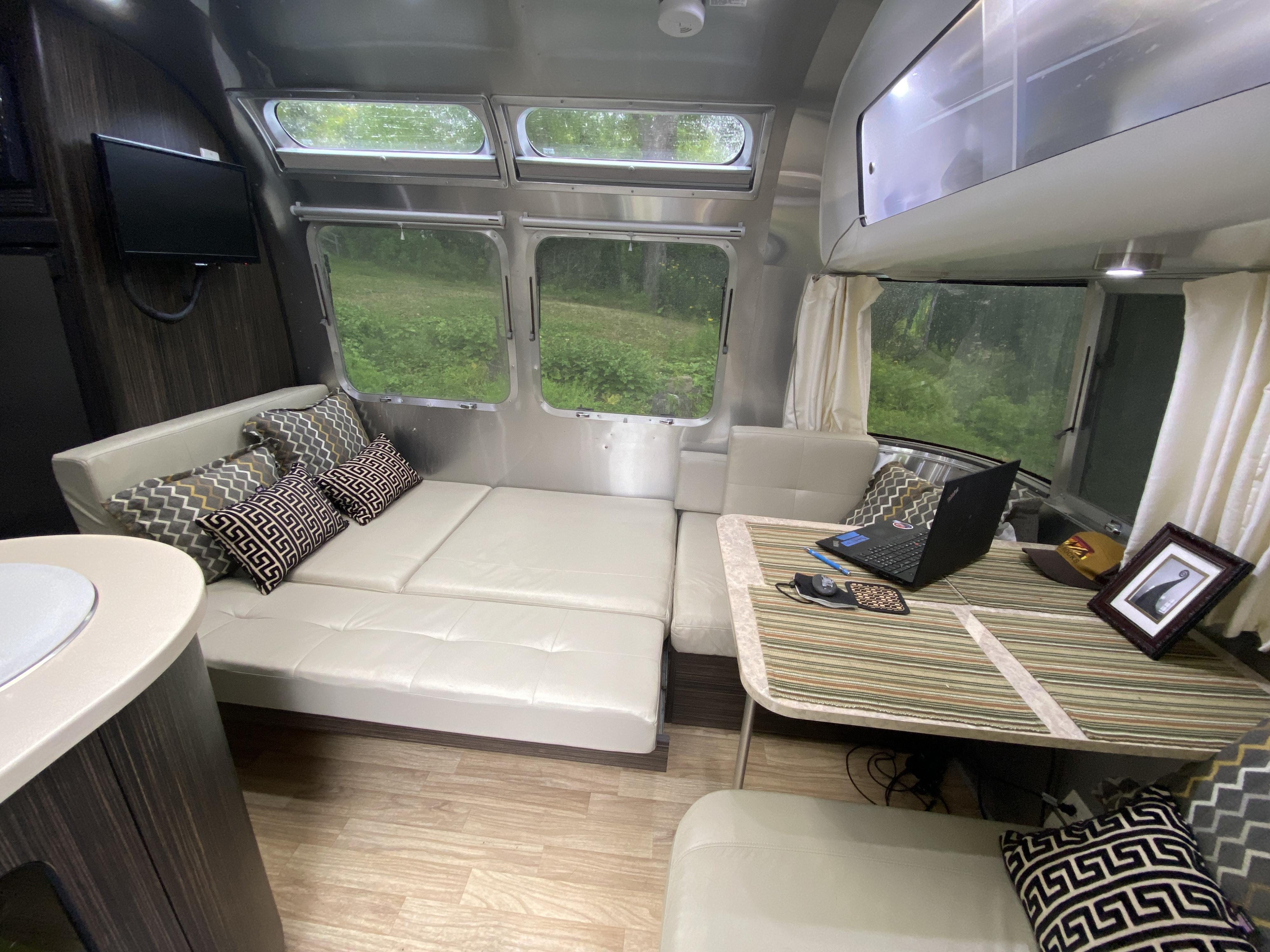 An inviting RV rental: A modern Airstream travel trailer with light seating, a table, and windows showing green scenery.. Airstream International 2014