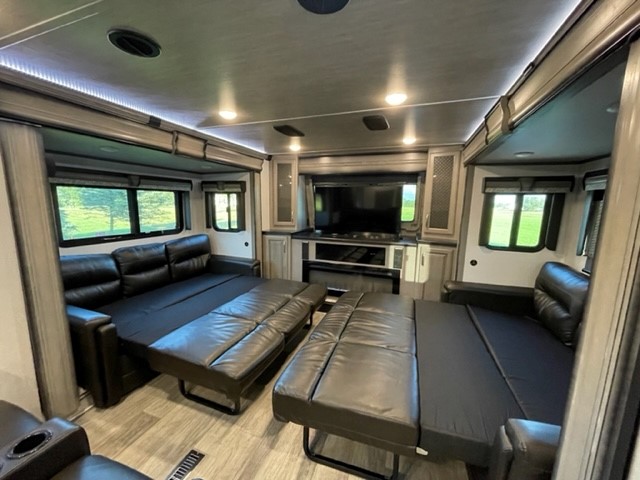 Modern RV rental interior showing two black sofas folded out into beds, providing ample sleeping space.. Keystone RV Montana 2021