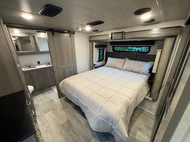 RV rental bedroom with queen bed, modern bathroom via sliding door. Bright, spacious interior for comfortable travel.. Keystone RV Montana 2021