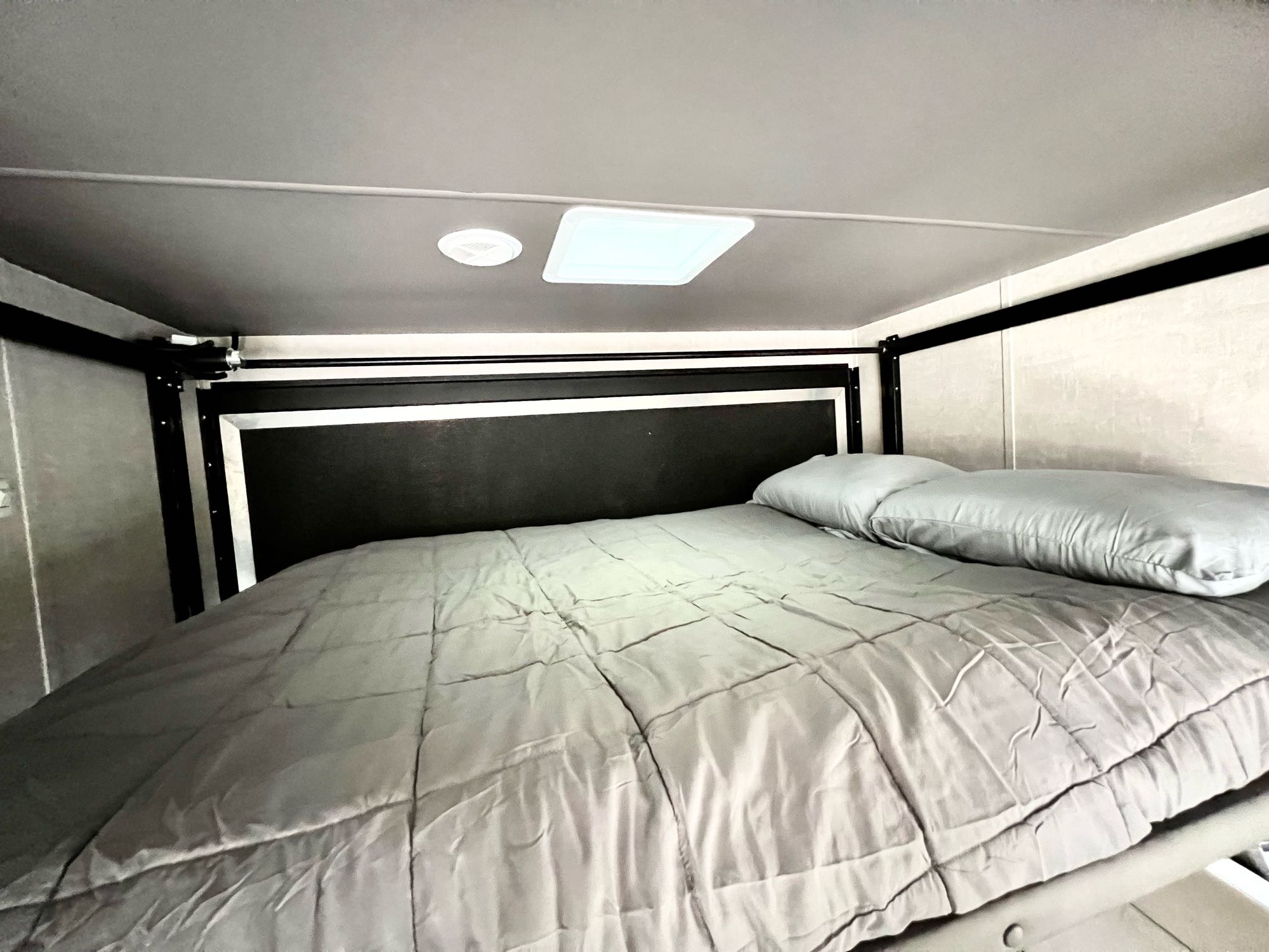 A comfortable bed with a gray comforter and pillow in an RV rental, perfect for restful sleep on your travels.. Eclipse Recreational Vehicles Stellar 2023