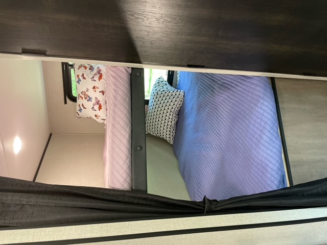 Two cozy bunk beds inside an RV rental, featuring soft pink and blue quilted bedding and decorative pillows.. Highland Ridge RV Olympia 2022