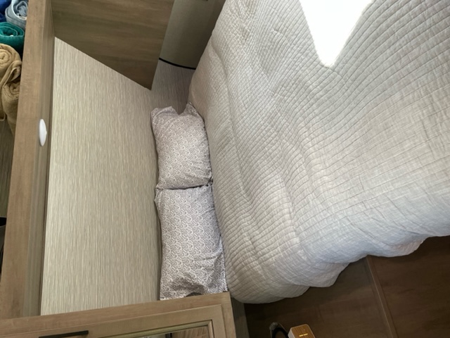 Cozy RV rental bedroom featuring a neatly made bed with pillows, alongside compact built-in storage.. Highland Ridge RV Olympia 2022