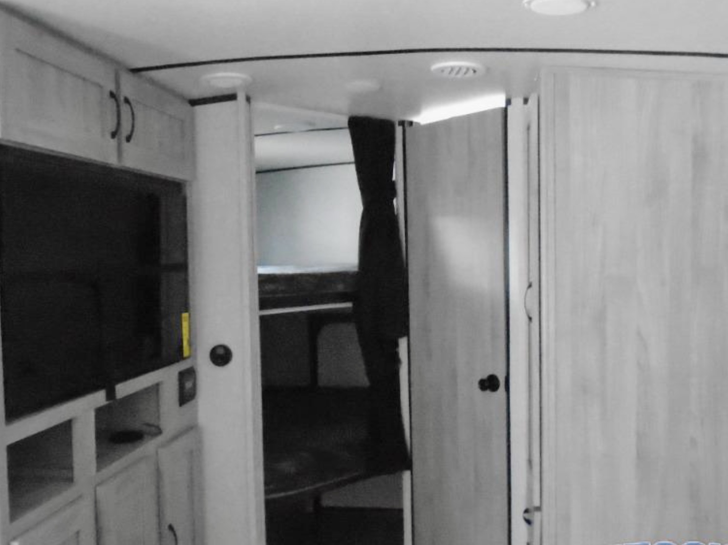 RV rental interior: TV, cabinets on left, hallway to bunk beds, and closet doors on right. Compact living space.. Other Other 2022
