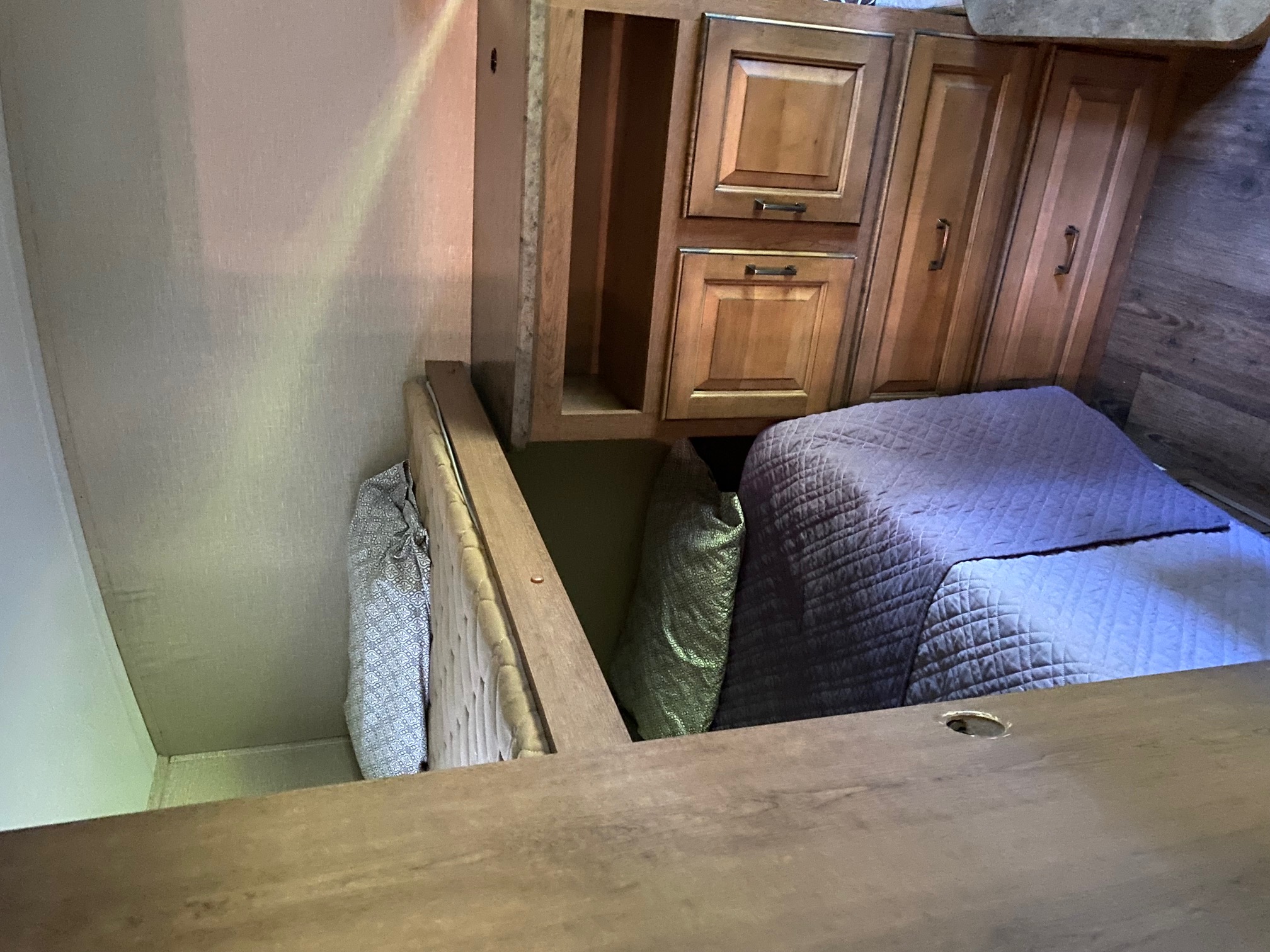 Inside an RV rental: a compact sleeping area with a quilted bed, wooden cabinets, and handy under-bed storage.. Cruiser RV Fun Finder 2014