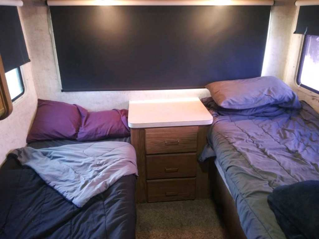 Cozy RV rental bedroom with two twin beds and a nightstand. Ideal for comfortable rest on your road trip.. Ford Tioga Montara 1992