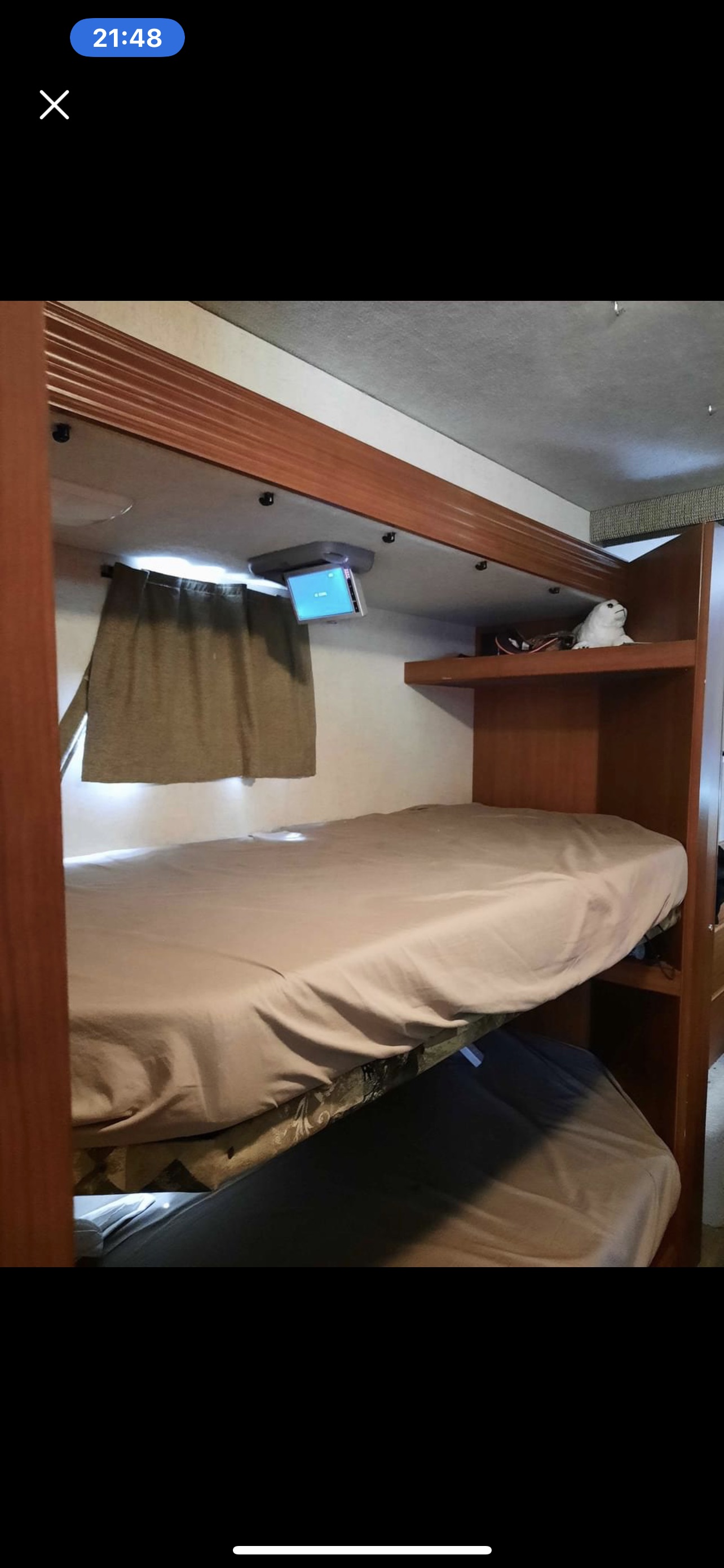 RV rental interior: Bunk beds, mounted TV, curtains, and shelf in compact sleeping area.. Jamboree Sport 2010