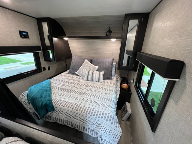 Cozy, compact RV rental bedroom with a striped bed and windows, featuring overhead storage.. Jayco Jay Flight SLX 2022