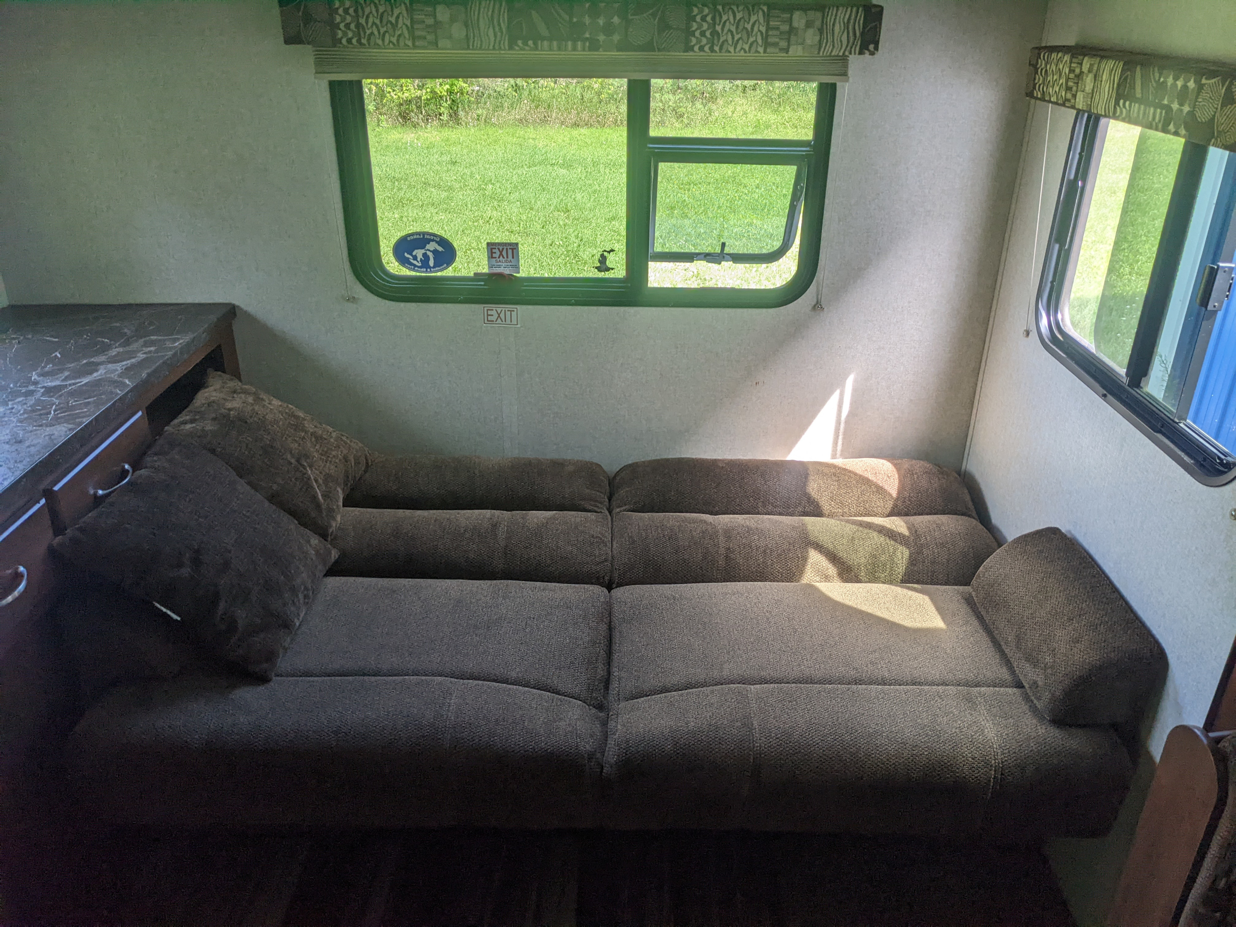 Comfortable RV rental interior with a sofa bed and large window showing a green outdoor view.. Jayco Jay Flight 2017