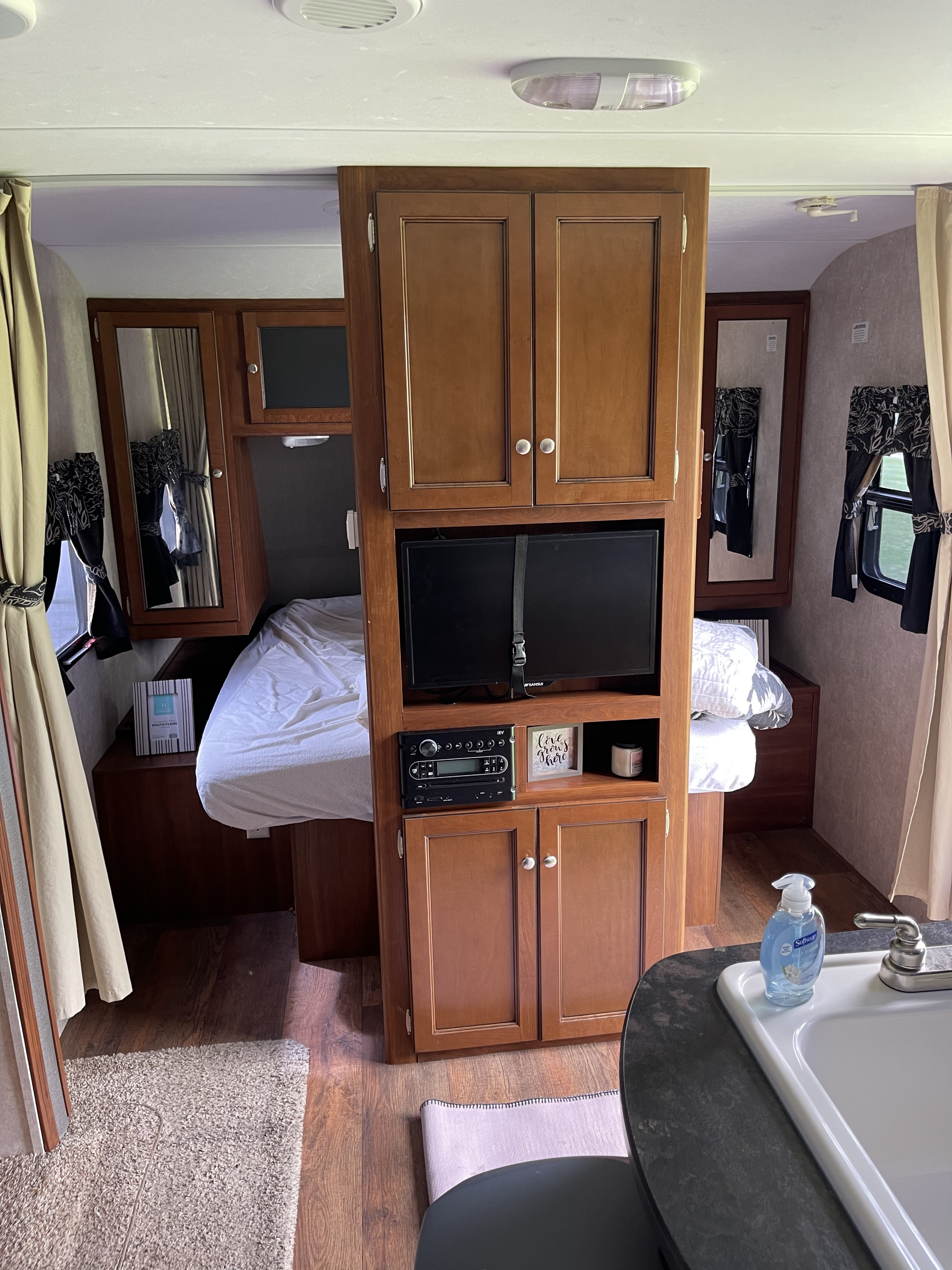 Cozy RV rental interior: bedroom with bed, TV, storage, & sink area, perfect for travel.. Keystone RV Bullet Ultra Lite 2015