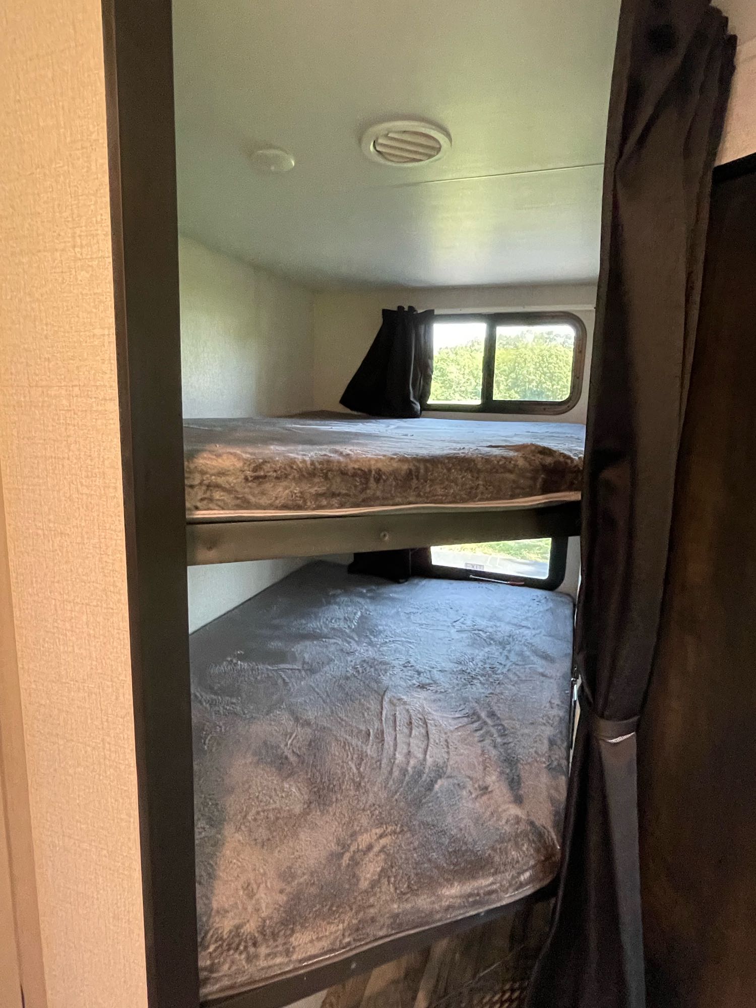 RV rental interior featuring practical bunk beds, equipped with mattresses, windows, and curtains.. Starcraft Super Lite 2022