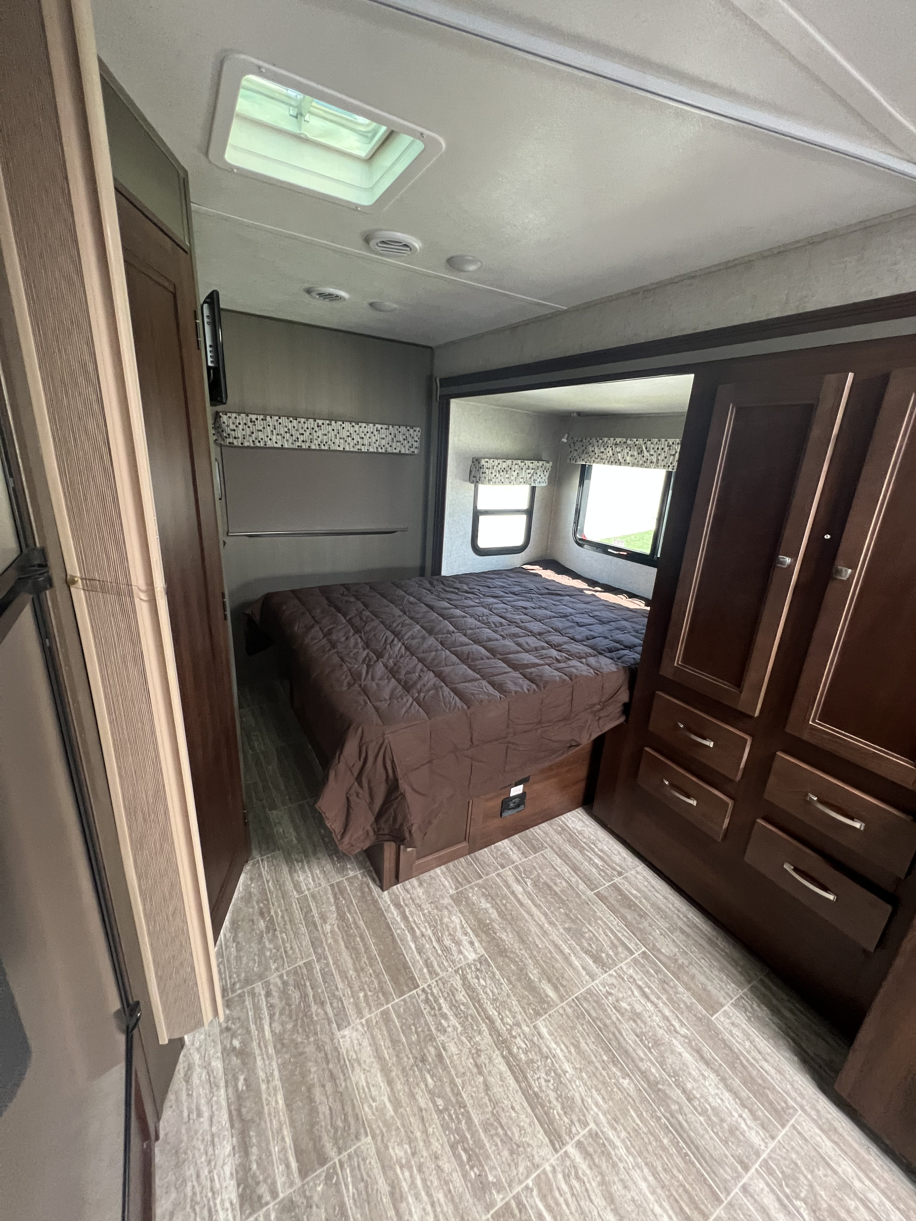 Spacious RV rental bedroom with a brown bed, bright windows, and built-in storage on the right.. Forest River Sunseeker MBS 2019