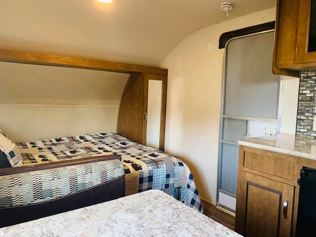 Cozy rv rental interior: bed with bear quilt, dinette, compact kitchen, and screen door entrance.. Forest River Salem Cruise Lite 2017