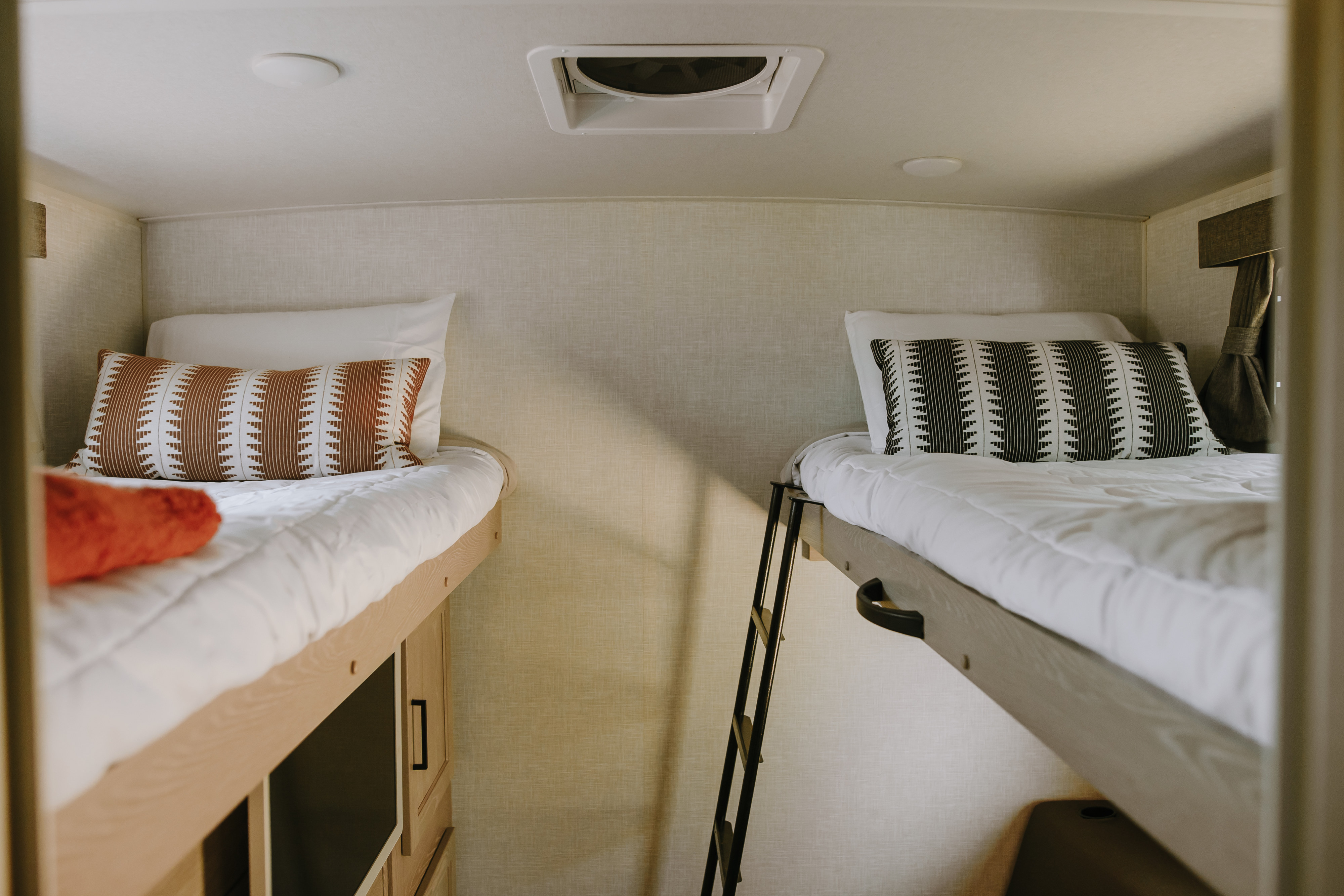 Cozy RV rental interior featuring two bunk beds with stylish pillows and an access ladder, perfect for travelers.. Forest River Rockwood Ultra Lite 2021