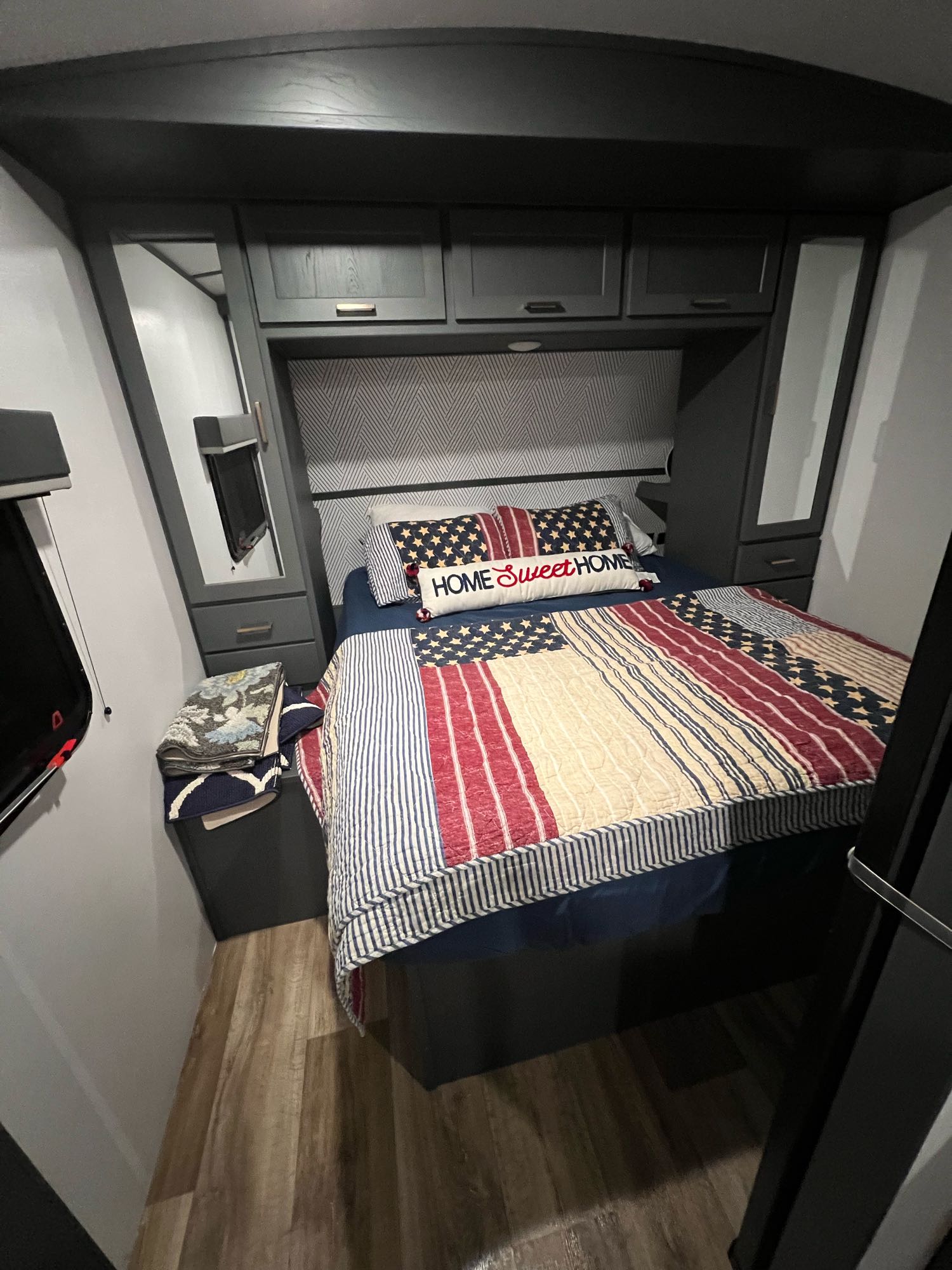 This RV rental offers a compact bedroom with a bed, patriotic quilt, overhead storage, and wood-look floor.. KEYSTONE Keystone Bullet250 bhs 2022