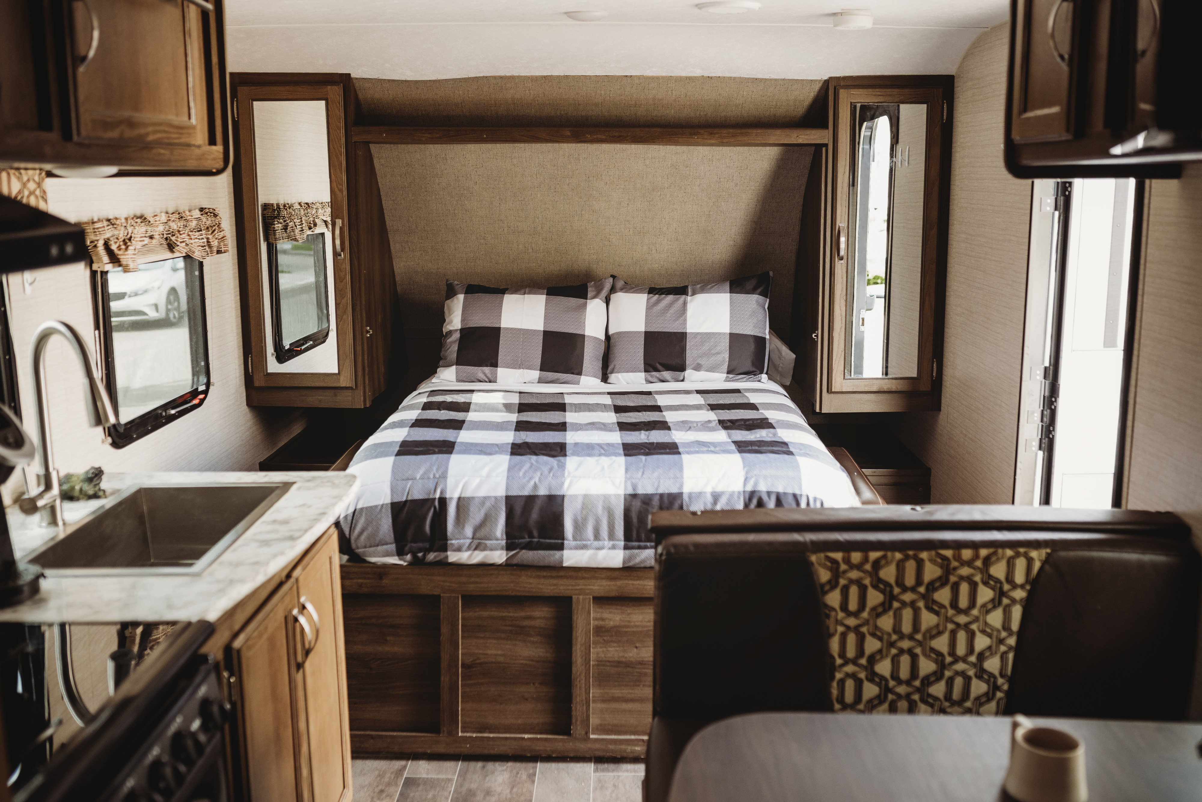 RV rental interior: cozy plaid bedroom, functional kitchen with sink, and comfortable dining booth.. Keystone RV Bullet Ultra Lite 2019