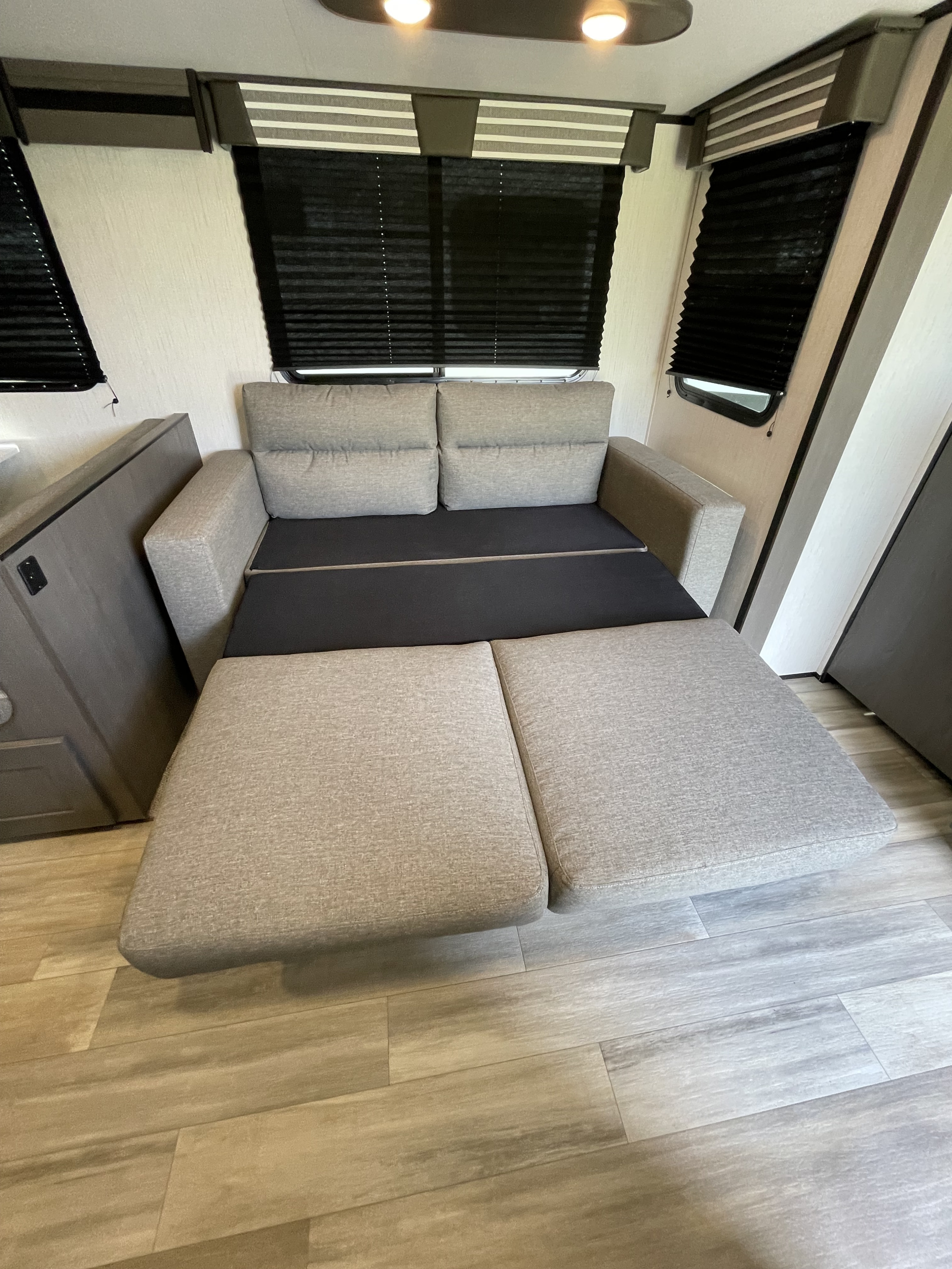 Compact RV rental living area featuring a pull-out sofa bed in a neutral grey fabric.. Heartland Mpg 2022