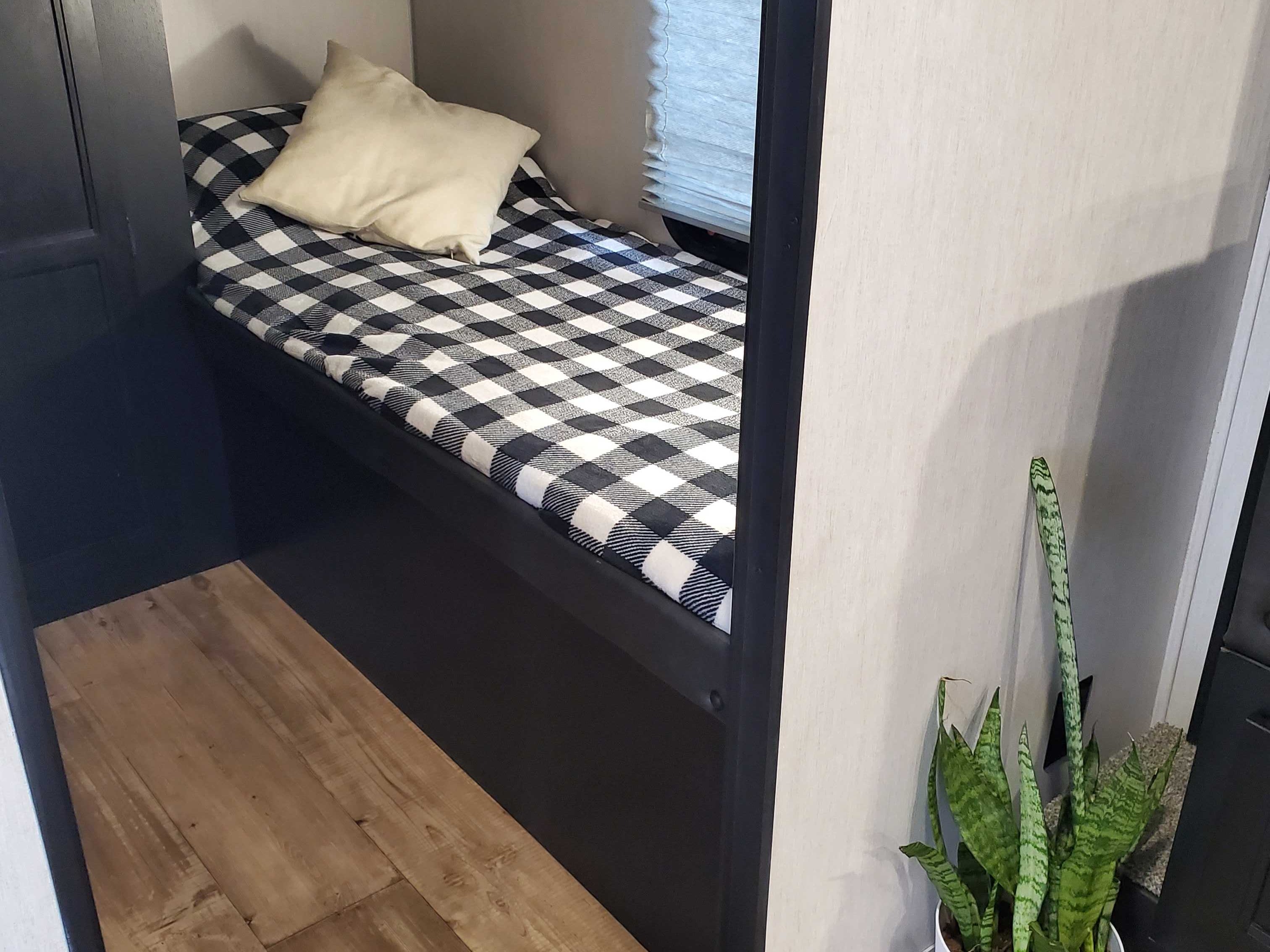 Inviting RV rental bunk bed, featuring a black & white plaid blanket & pillow. Cozy interior space for your adventure.. Forest River Cherokee Grey Wolf 2022