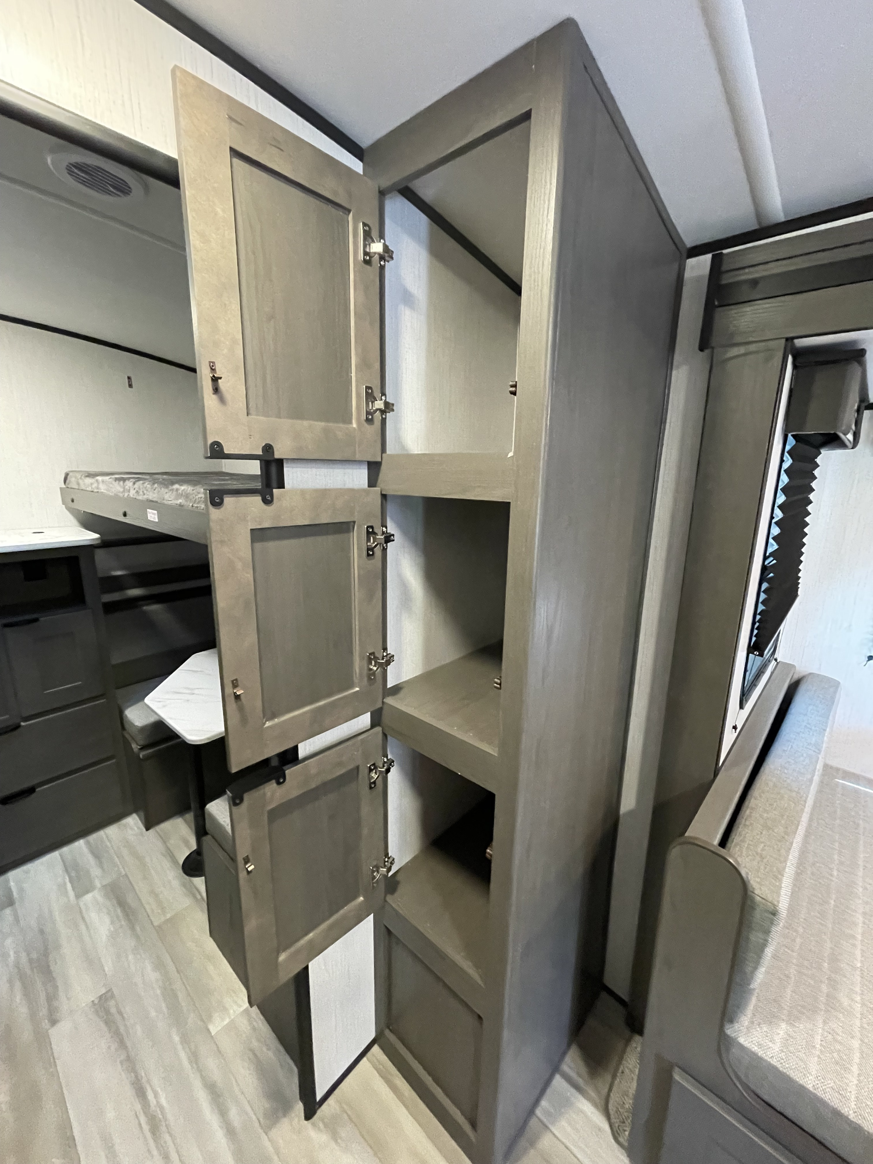 RV rental interior shows an open storage cabinet, bunk bed, and dinette seating with a table. Features gray and light tones.. Heartland Mpg 2022