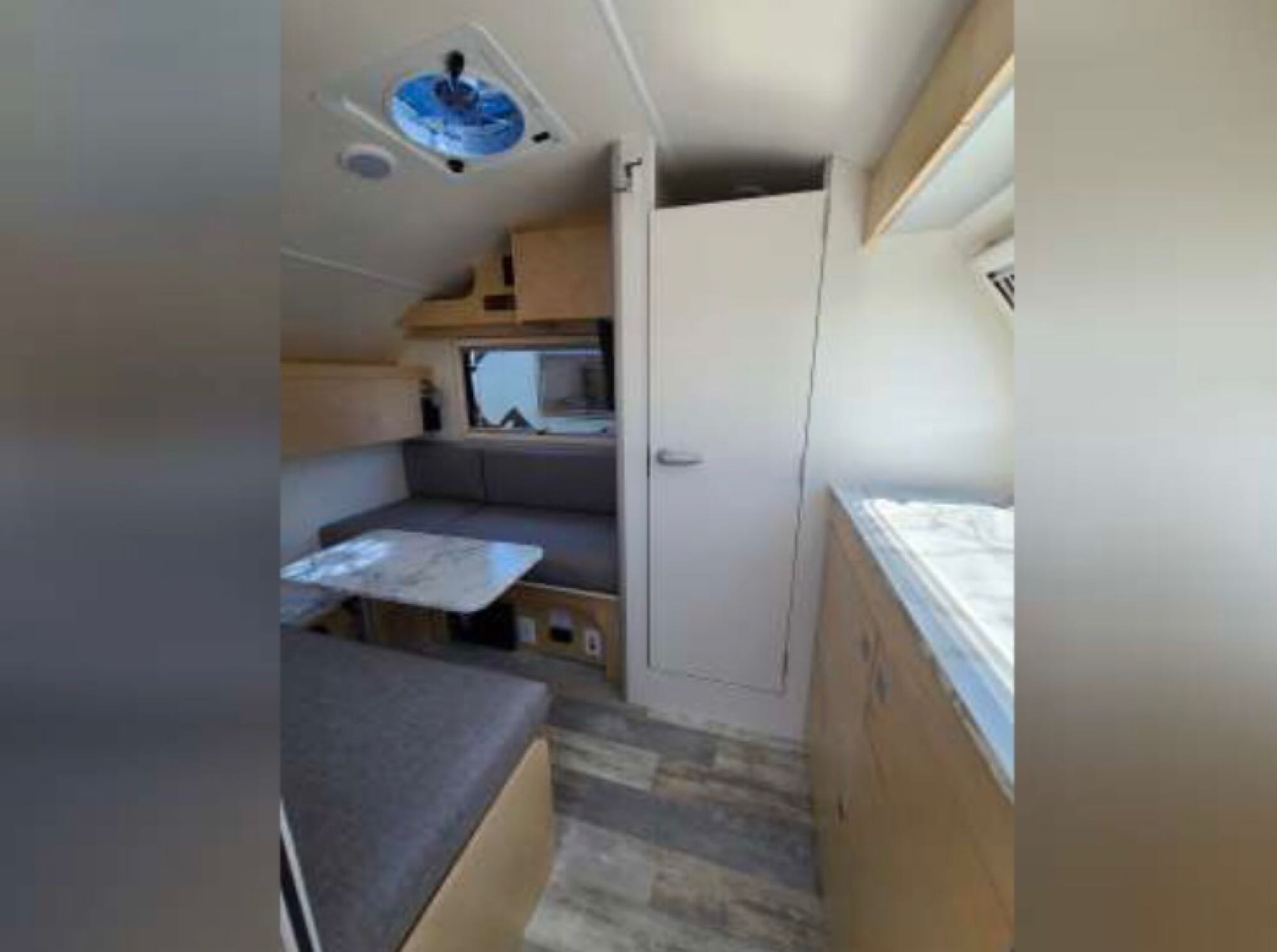 Inside a modern RV rental: view of the dinette with gray cushions, a ceiling fan, and light wood flooring.. Nucamp TAB 320 CS-S 2022