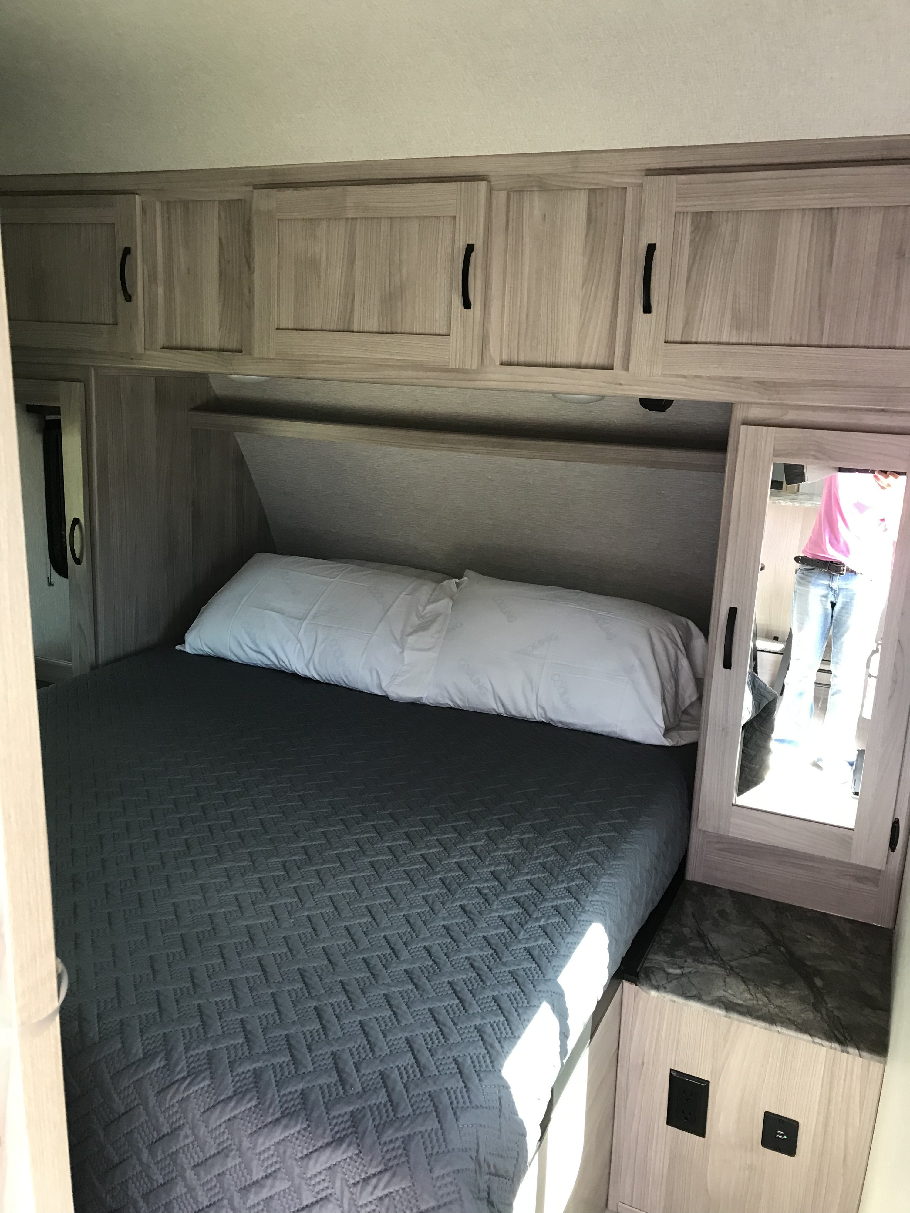 Cozy RV rental bedroom featuring a comfortable bed, overhead storage, and mirrored closet with power outlets.. Other Other 2022