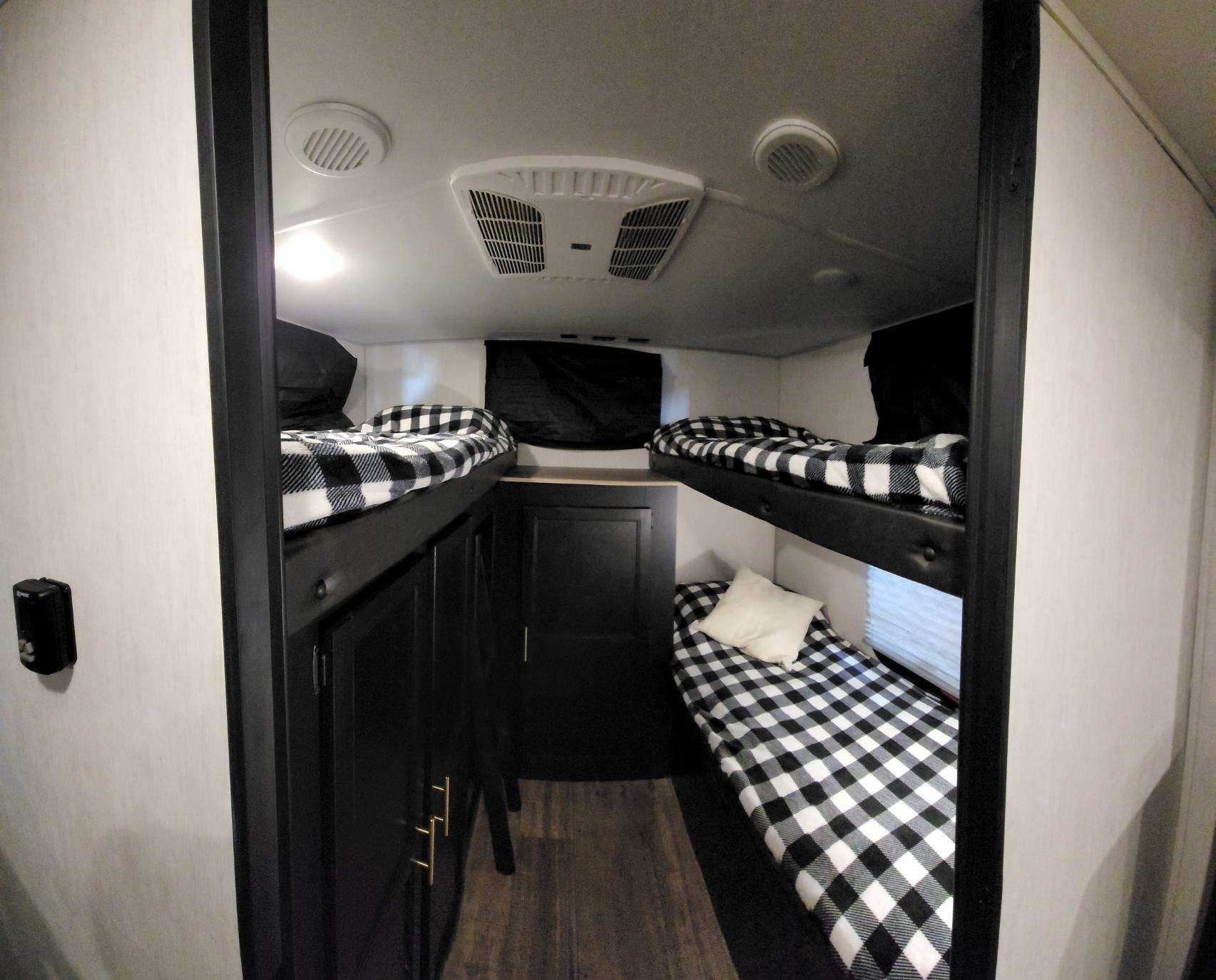 RV rental bunkhouse: Cozy interior with four black and white plaid bunk beds and storage cabinets.. Forest River Cherokee Grey Wolf 2022