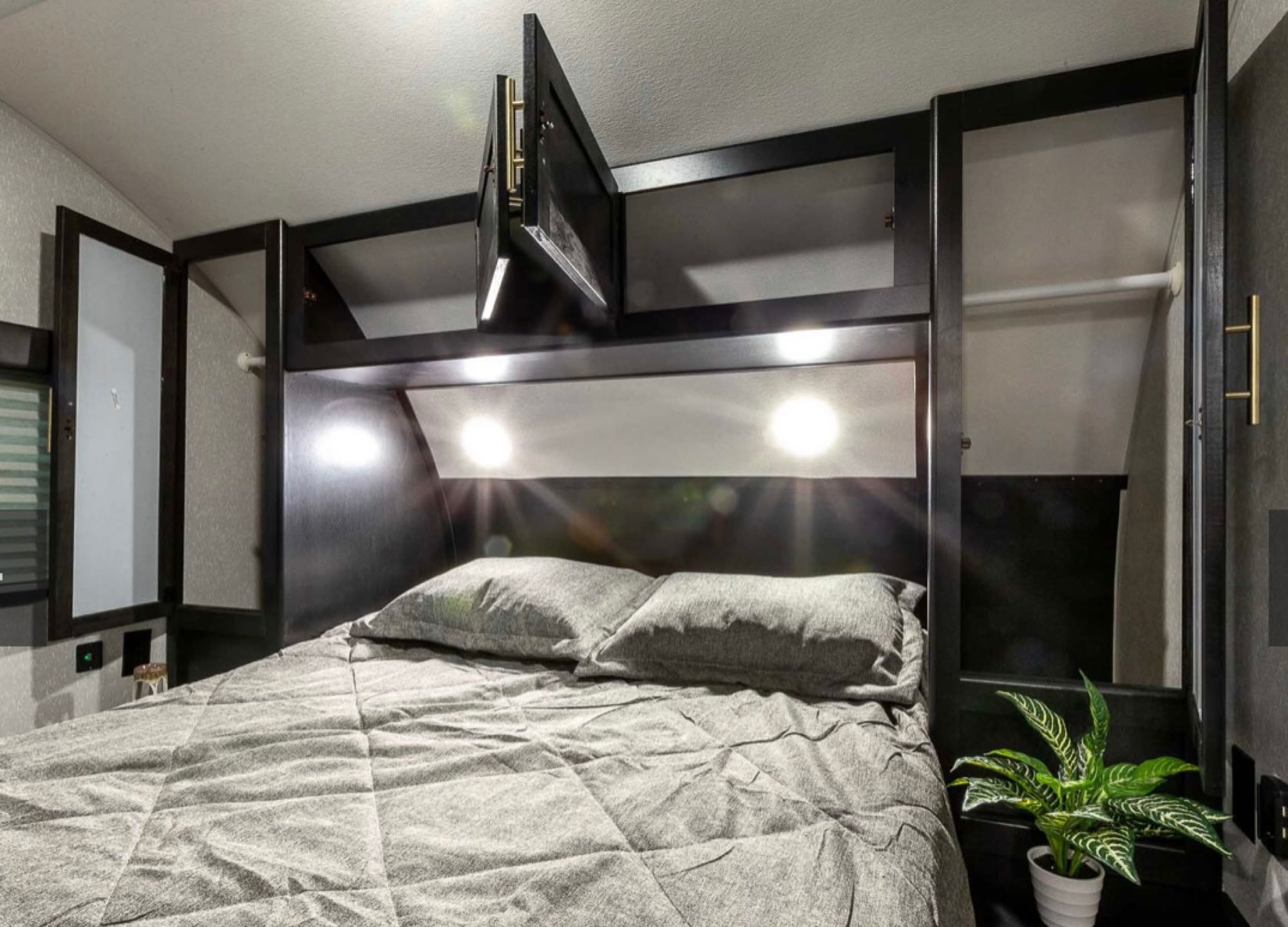 RV rental bedroom: a cozy gray bed, integrated lighting, and practical overhead storage. Ready for your next adventure.. Forest River Cherokee Grey Wolf 2022