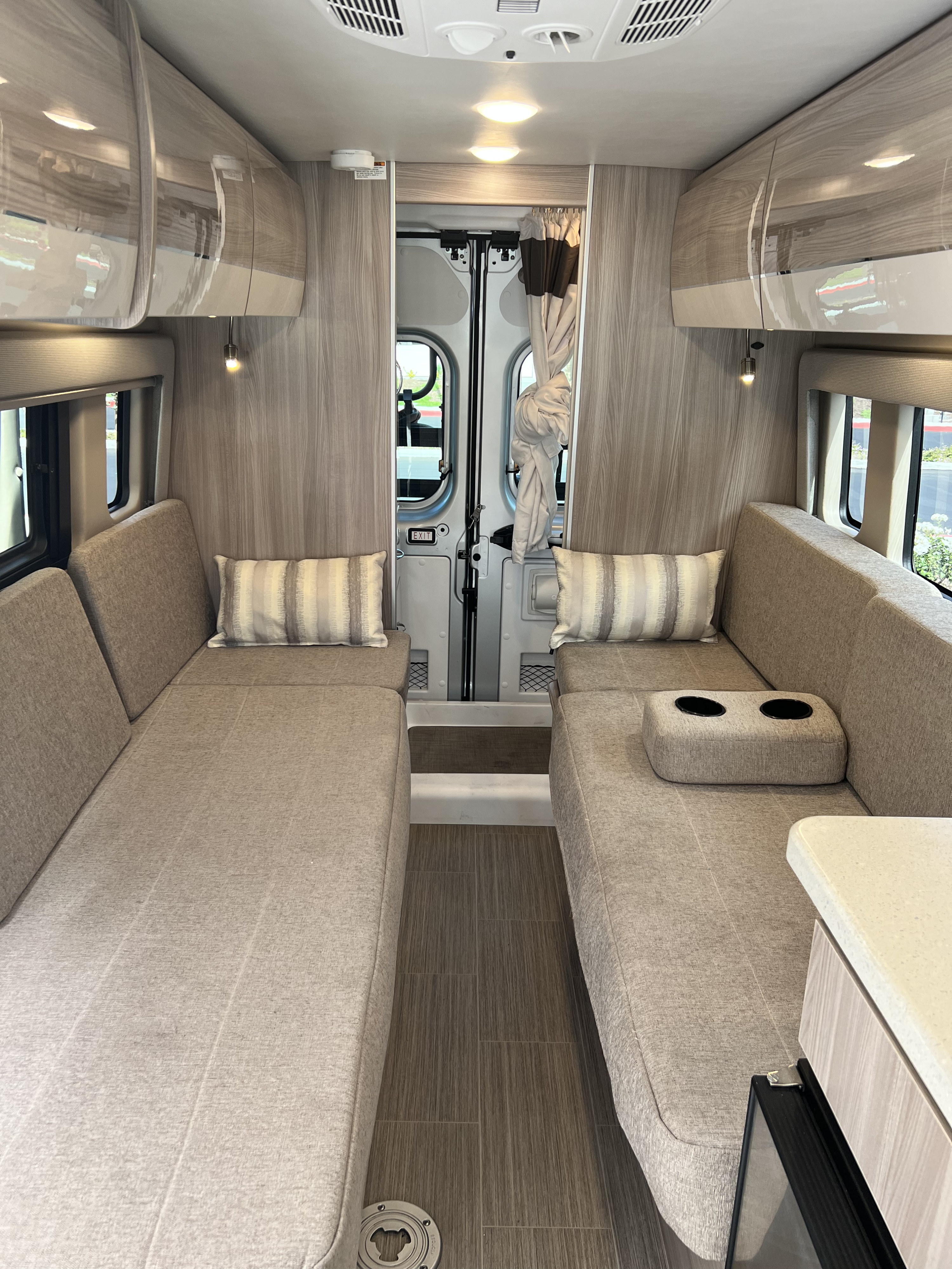 This inviting RV rental interior features convertible lounge seating, overhead storage, and rear access for comfy travels.. Thor Sequence 2023