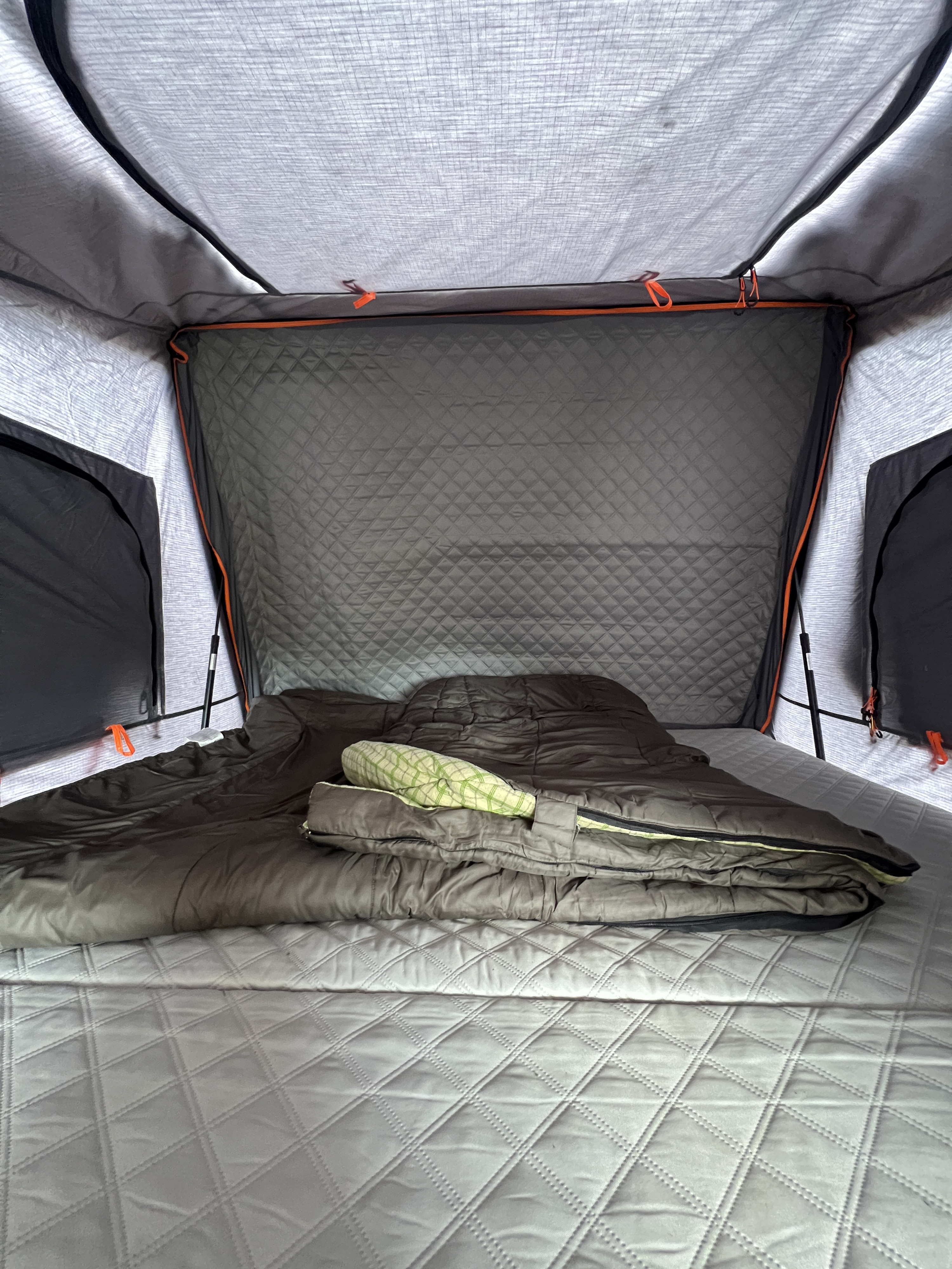 Cozy RV rental interior with a comfortable quilted bed, sleeping bag, and green pillow, ready for mobile adventures.. Land Rover Range Rover Sport 2006