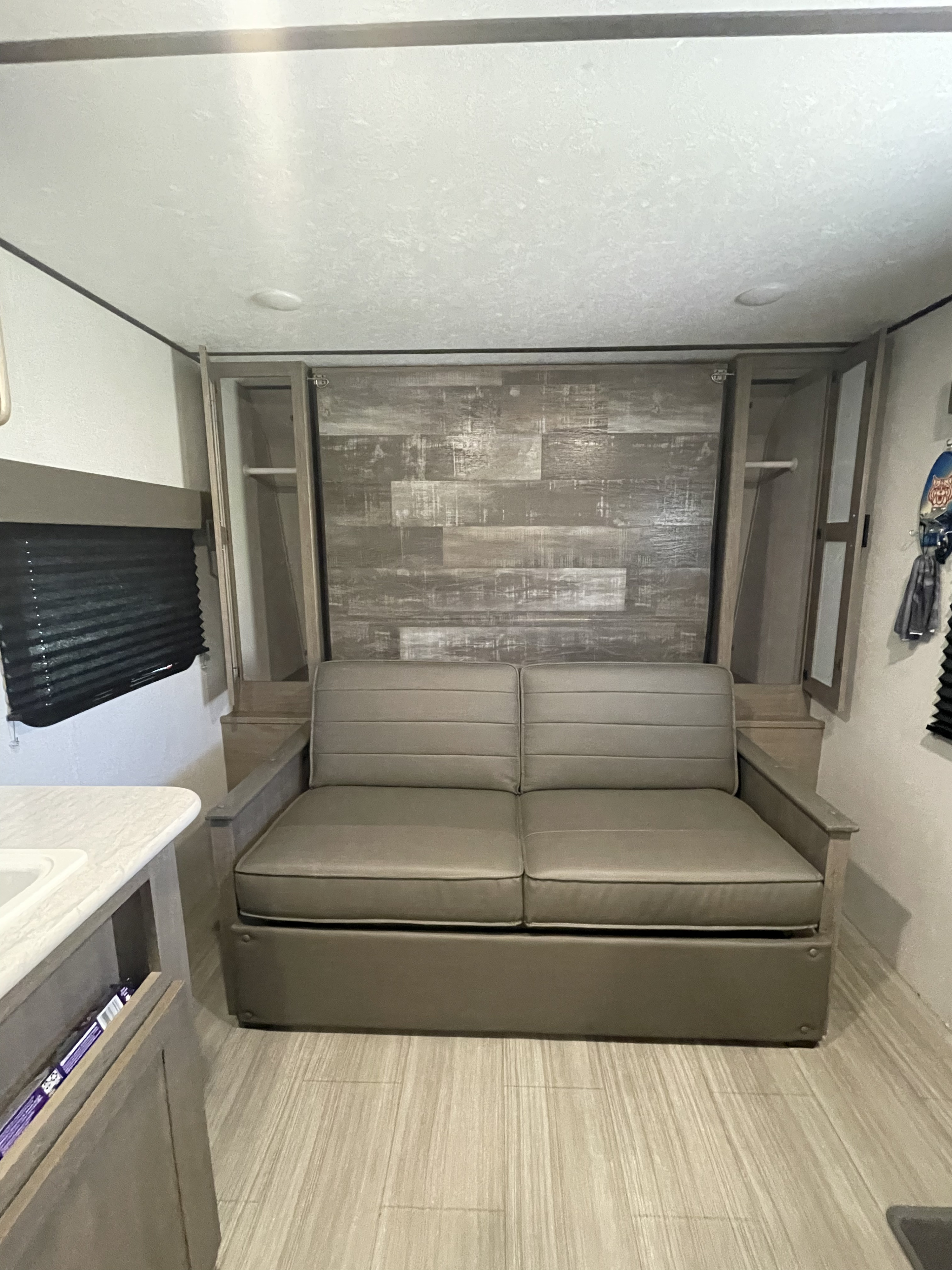 RV rental: Modern interior with a grey convertible sofa, built-in storage, and wood-patterned wall.. Keystone Travel trailer Hideout 2021