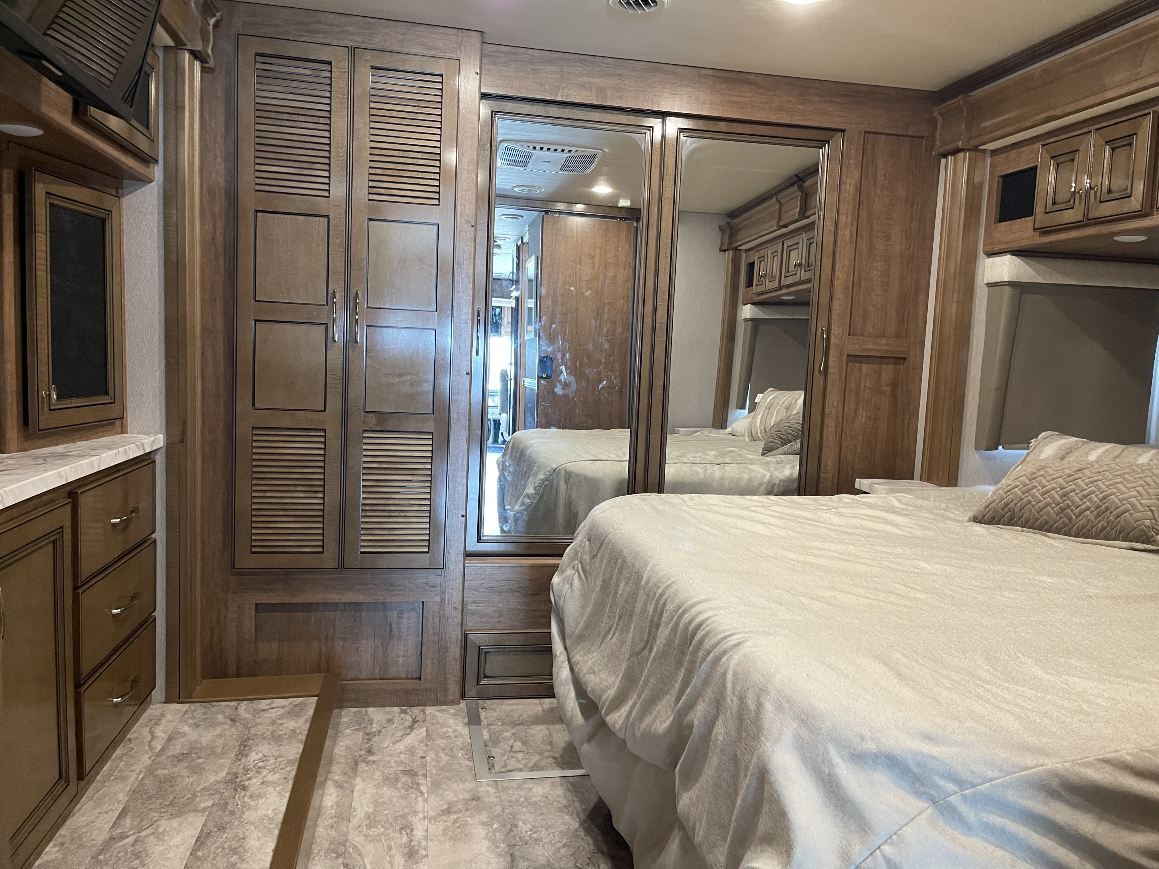 Spacious RV rental bedroom with wood cabinetry, a comfortable bed, and mirrored wardrobe, offering home-like comfort.. Fleetwood Frontier 2022