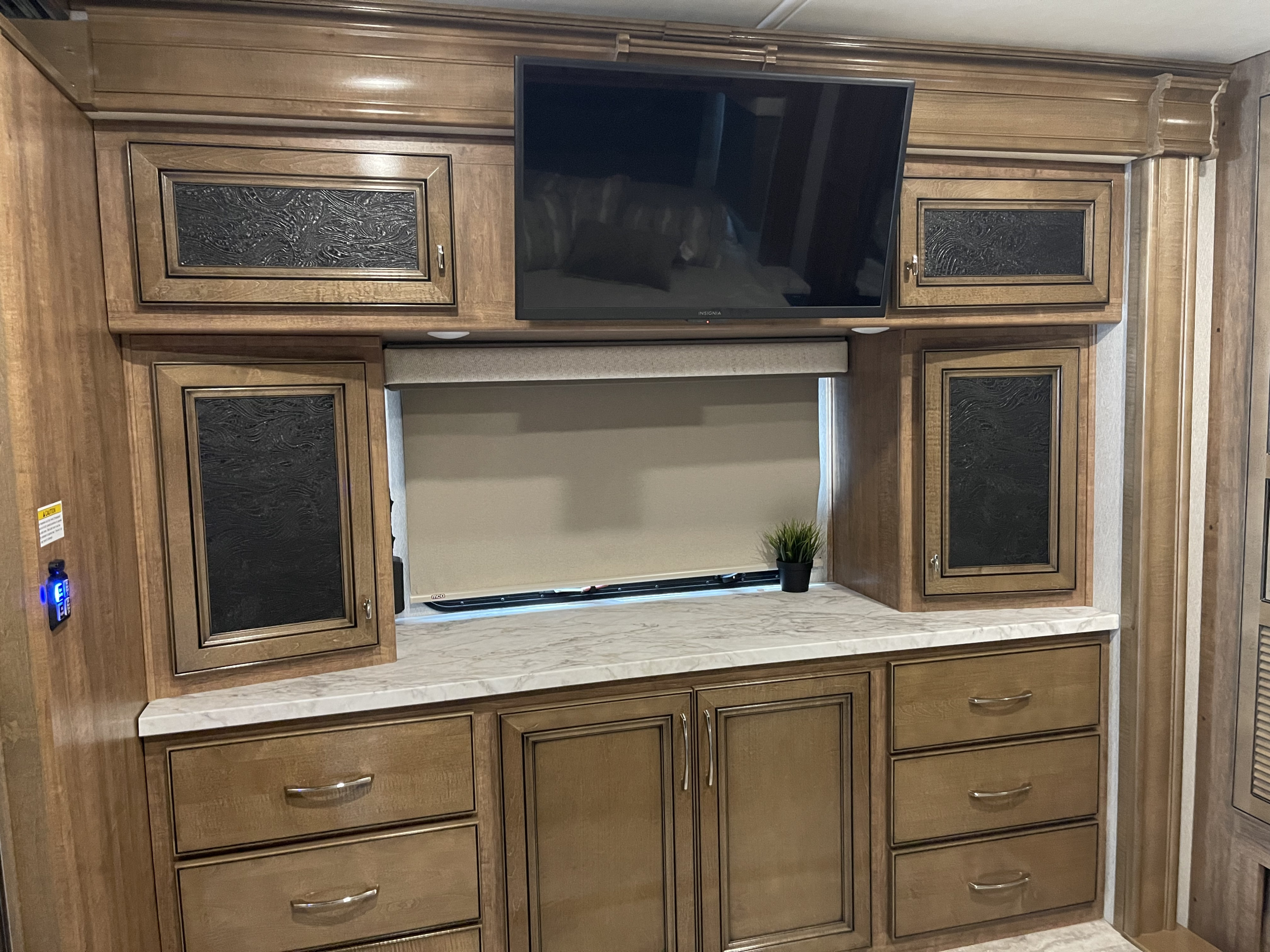 Modern RV rental bedroom setup with built-in wooden cabinets, flat-screen TV, and countertop. A cozy, functional interior.. Fleetwood Frontier 2022