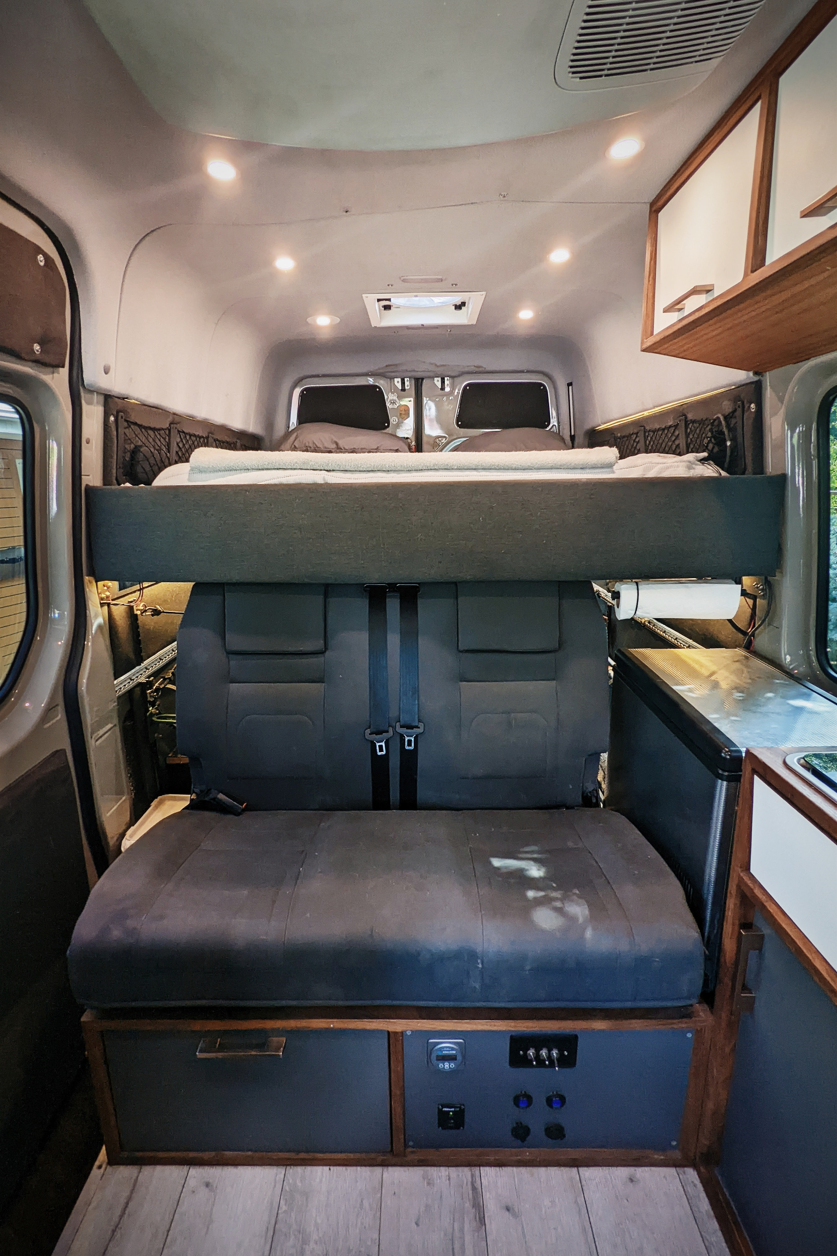 RV rental interior: elevated bed over rear seats, kitchen, and power control panel. Ready for your camper van trip.. Mercedes-Benz Sprinter 2017