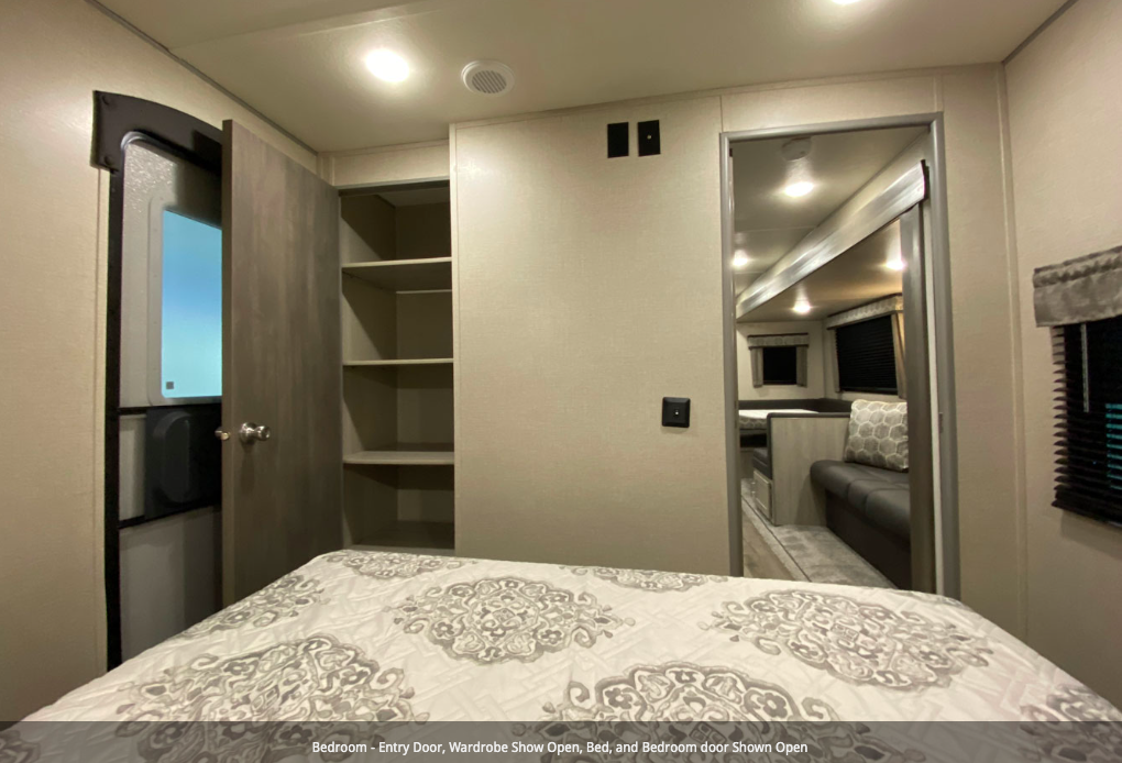 Explore this rv rental's cozy bedroom, featuring an open wardrobe, bed, and an open door to the living area.. Forest River Coachmen Catalina Legacy 2022