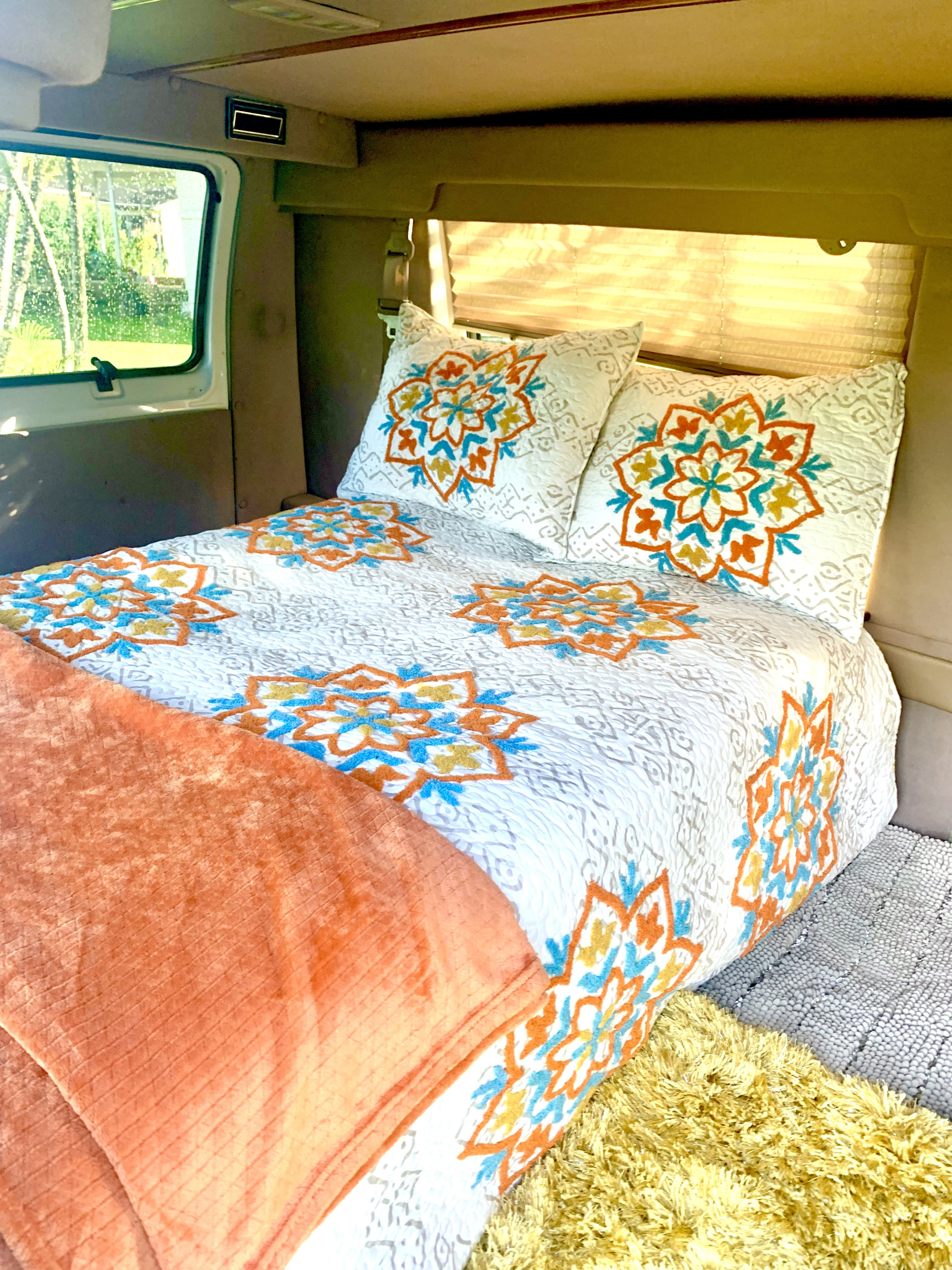 Cozy RV rental interior with a comfy bed, white and colorful mandala bedding, and a scenic window view.. Dodge Ram 1500 1999