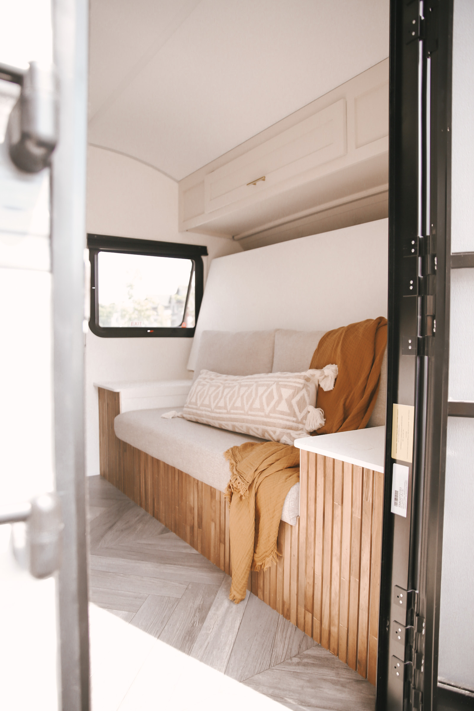 Bright RV rental interior: sofa with wood slat base, herringbone floor, and window for natural light.. Forest River Salem FSX 2021
