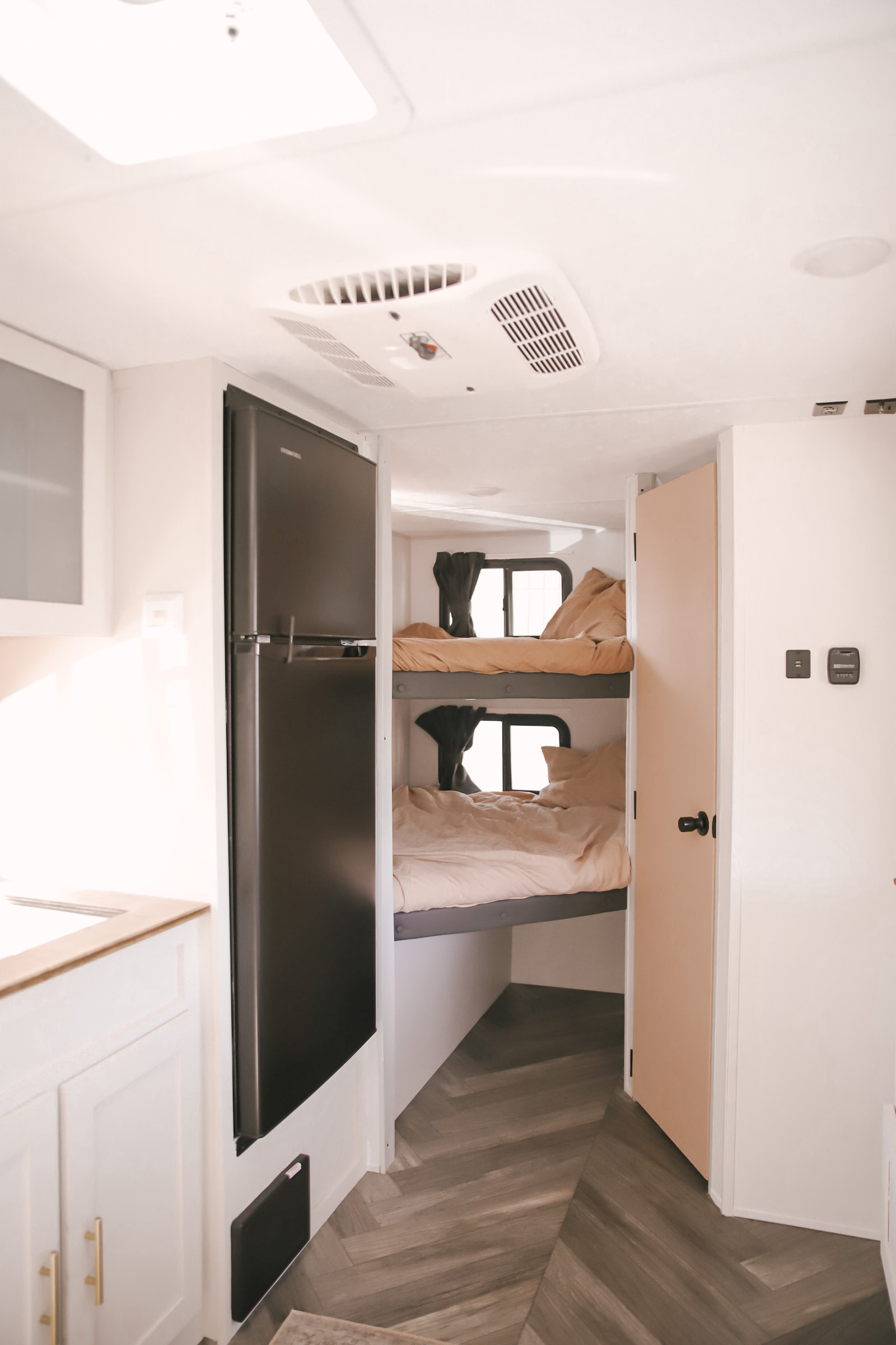 Bright rv rental interior featuring a modern kitchen area with a large fridge, and cozy bunk beds visible through an open doorway.. Forest River Salem FSX 2021