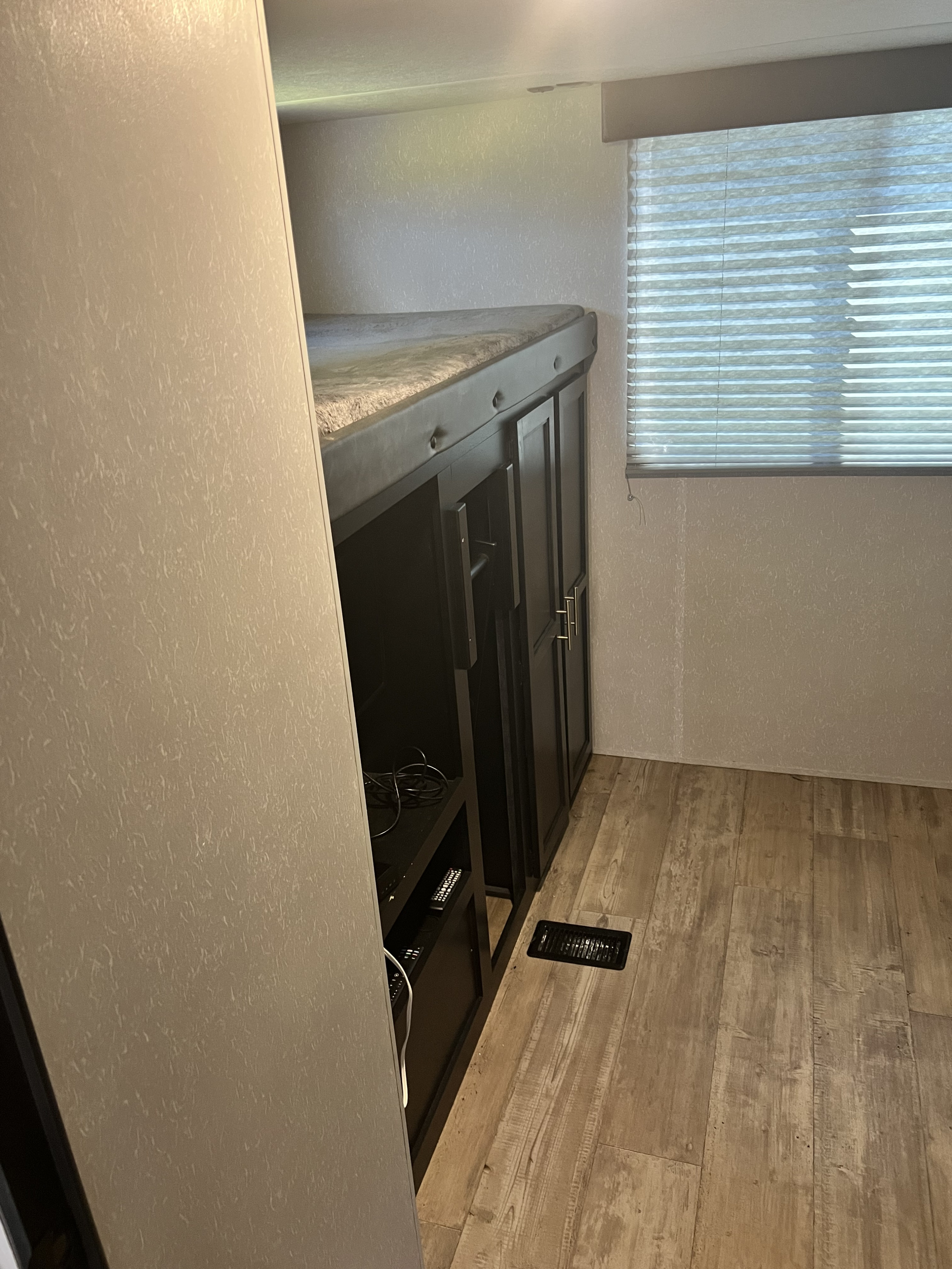 RV rental interior: cozy bunk bed over dark storage, window with blinds, and wood-look floor for comfortable travel.. Forest River Cherokee 2021