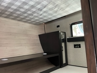 Explore the cozy bunk bed area of this RV rental, featuring a checkered ceiling, wood walls, and a side window for comfortable travel.. Jayco Jay Flight SLX 8 2023
