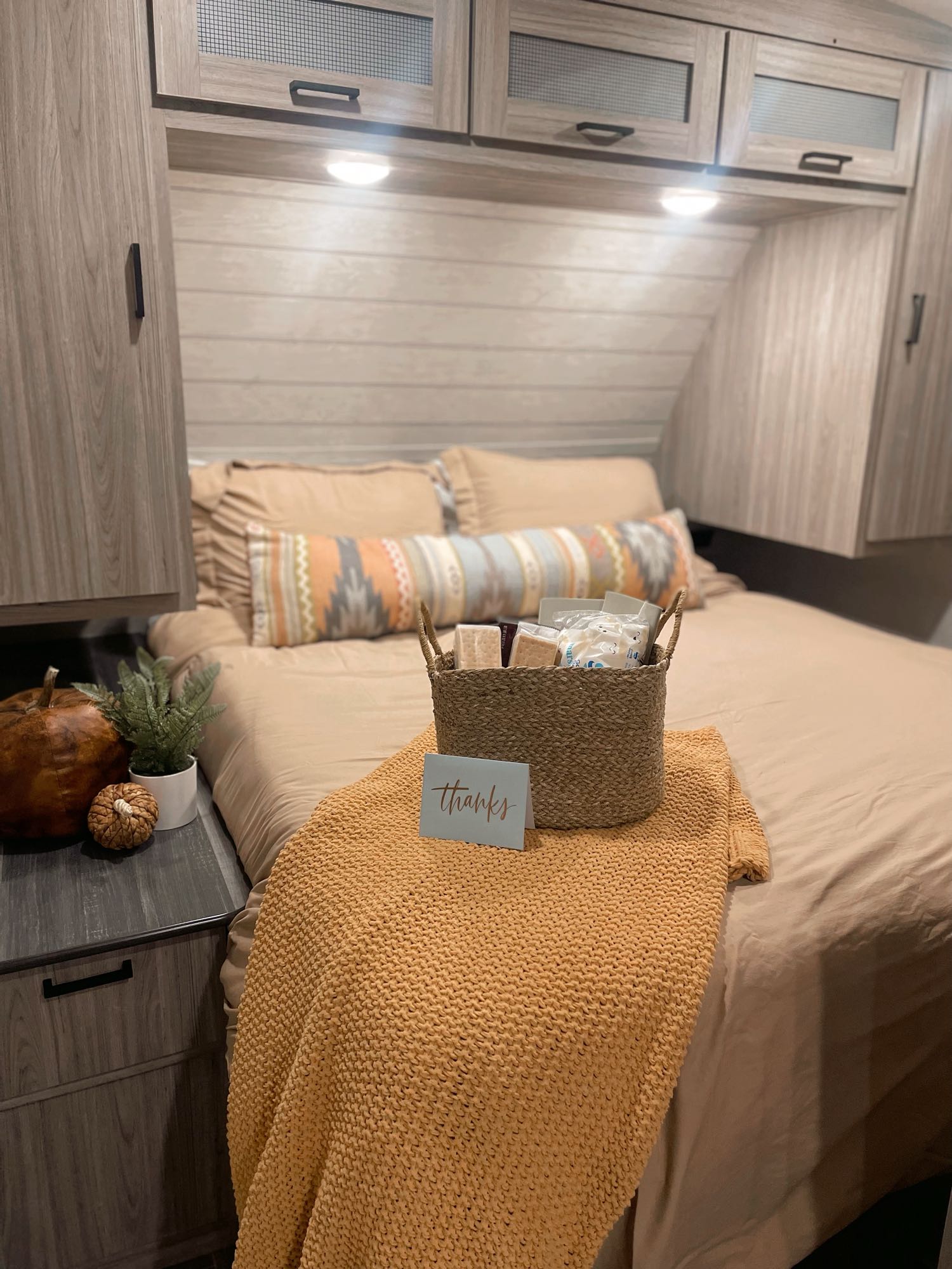 Cozy RV rental bedroom featuring light wood tones, a welcome basket, and warm fall decor for a comfortable stay.. Keystone RV Passport GT 2021
