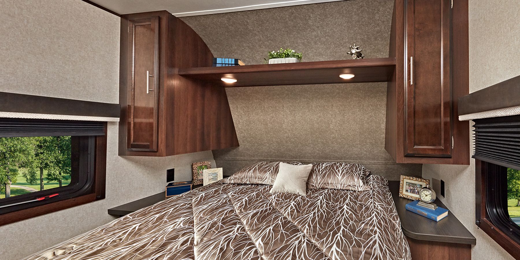 RV rental bedroom: Features a cozy bed with branch-patterned comforter, overhead storage, reading lights, and side windows.. Jayco Jay Flight SLX 2019