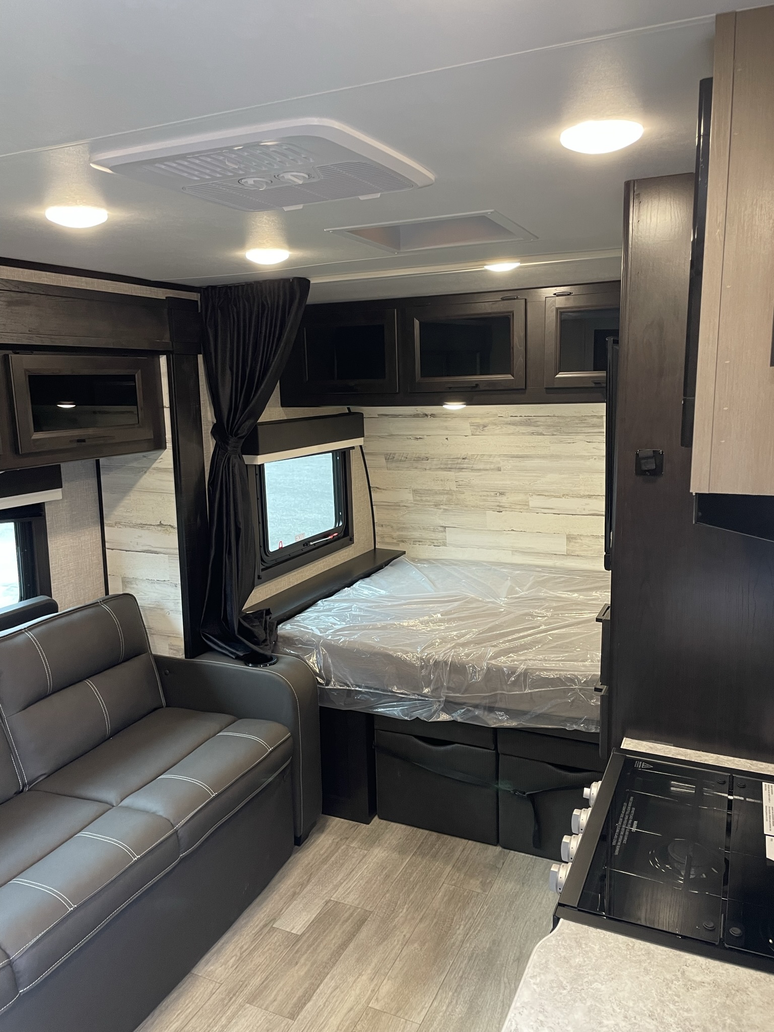 RV rental interior: modern living area with sofa, bed, kitchen, and overhead storage. Well-lit and compact space.. Jayco Jay Feather Micro 2022