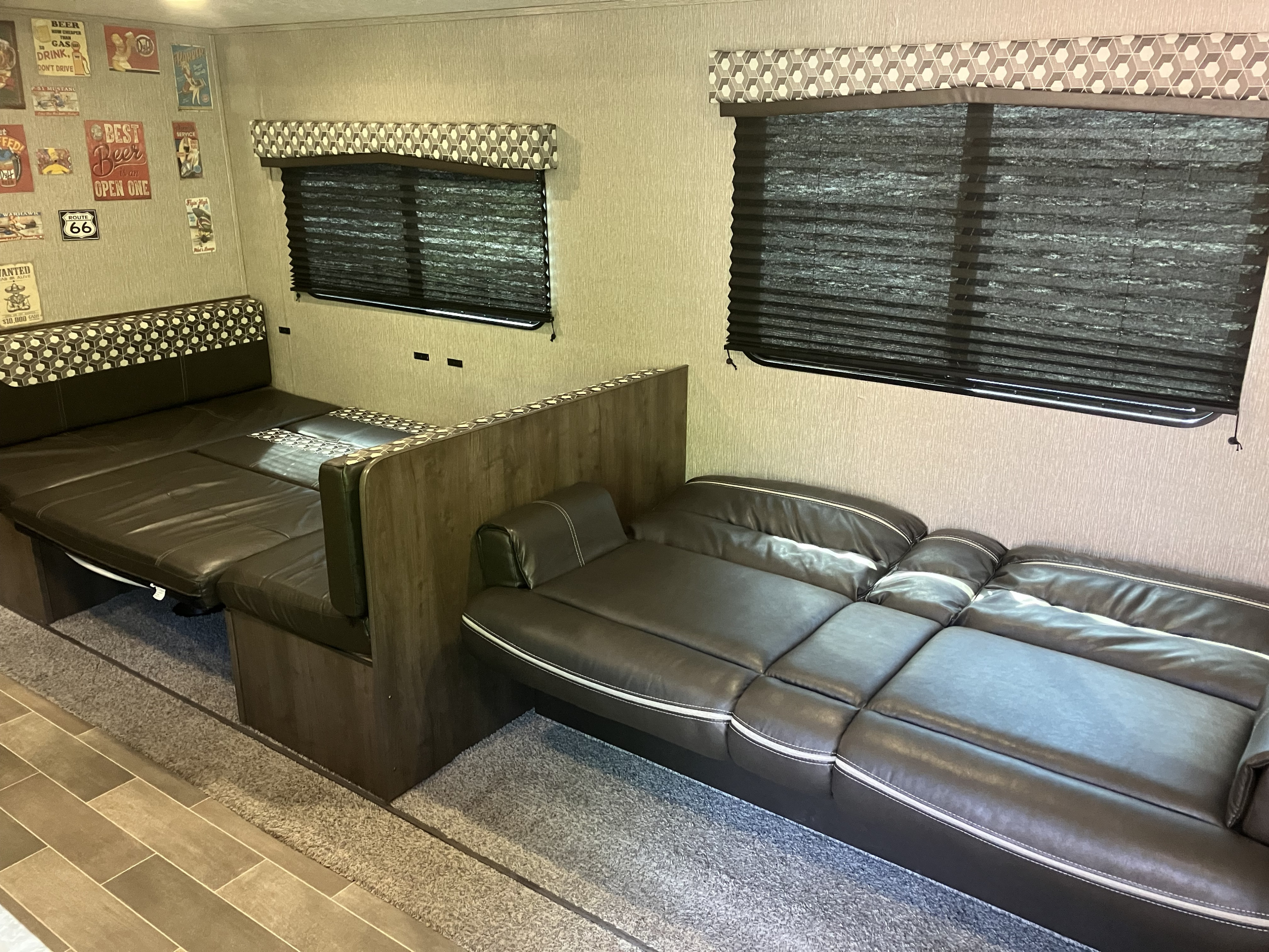 Comfortable RV rental interior with a dark brown convertible dinette bed, reclining sofa, and decorative walls.. Dutchmen Coleman Lantern 2019